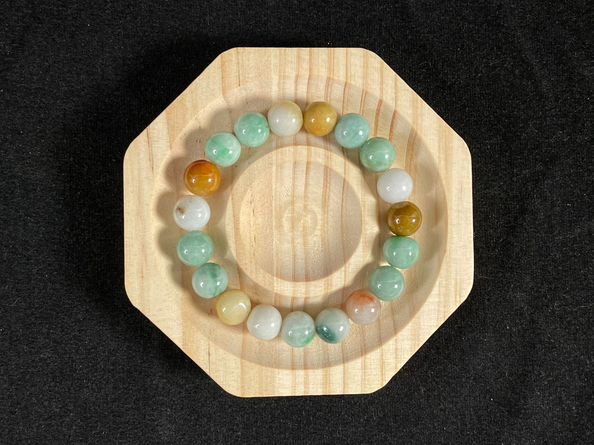 A jade bead strand predominantly green with brown, gold, and white accents.