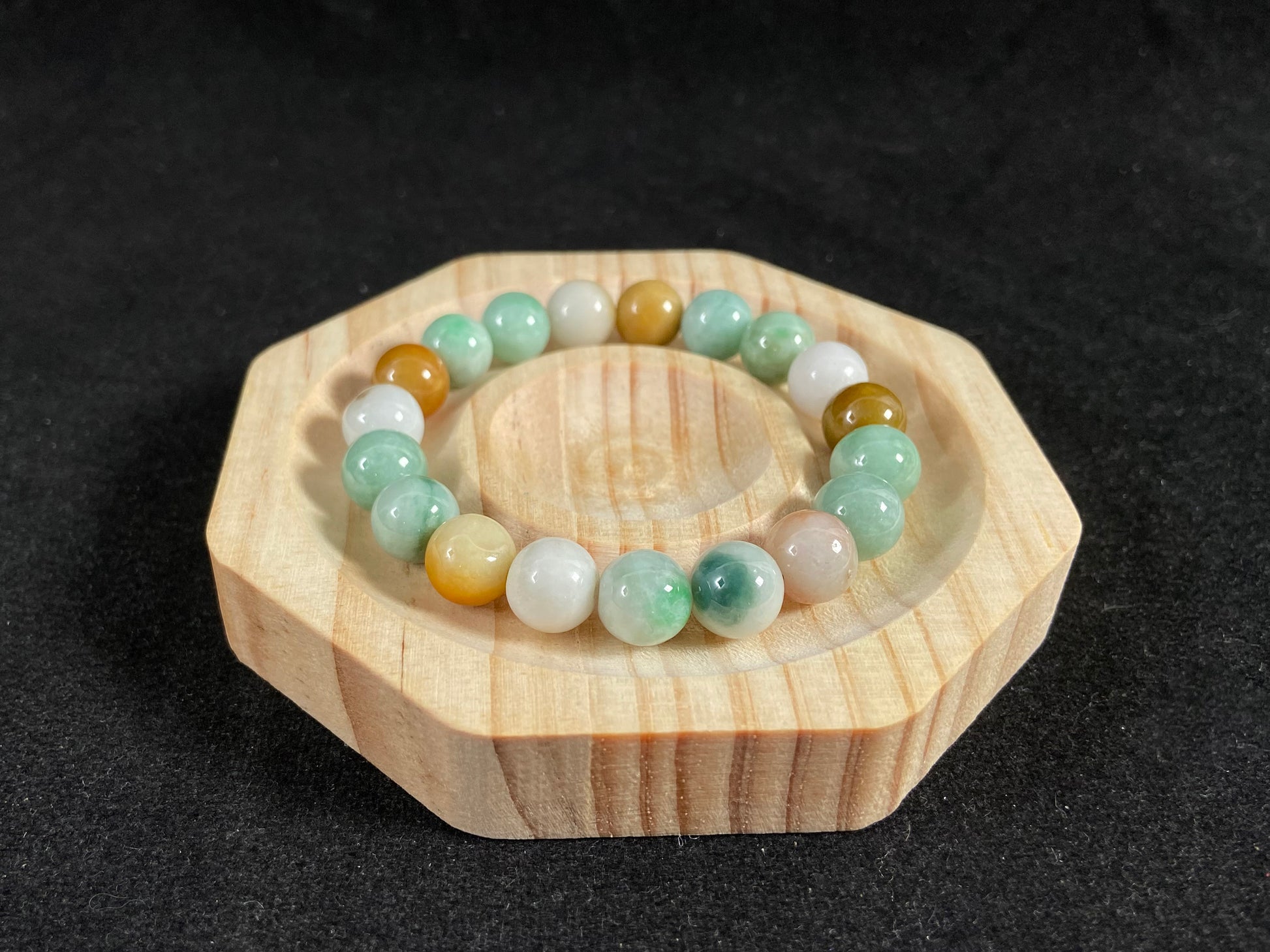 A jade bead strand predominantly green with brown, gold, and white accents.