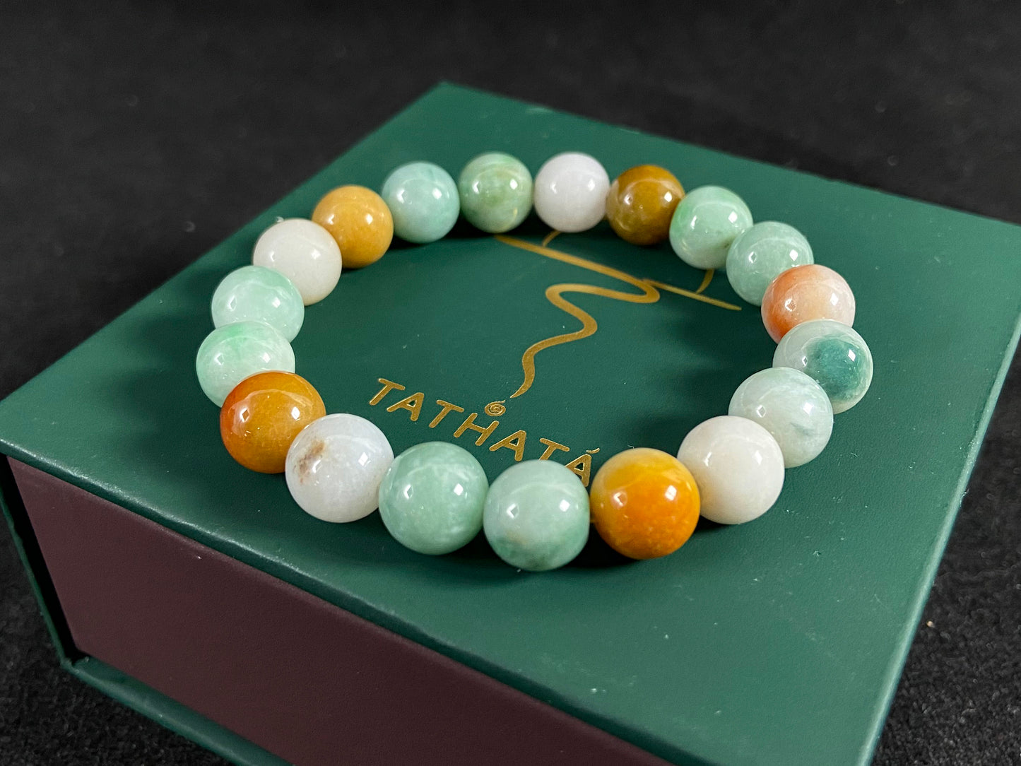 A jade bead strand predominantly green with brown, gold, and white accents.