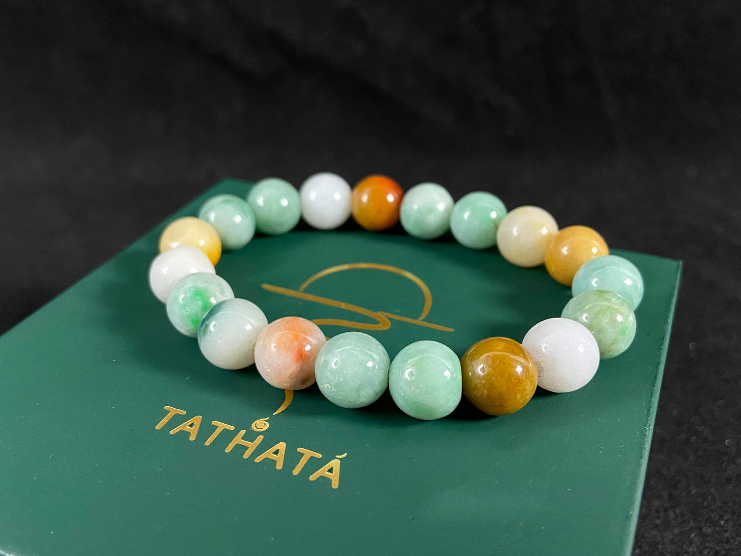 A jade bead strand predominantly green with brown, gold, and white accents.