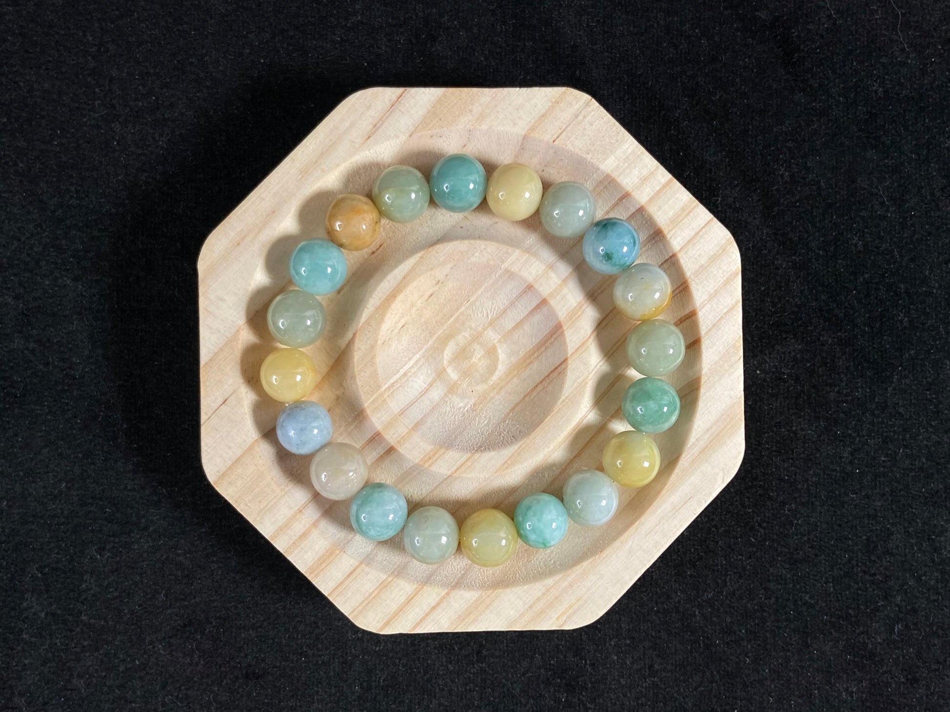 A strand of uniform jade beads in seafoam green, brown, yellow, light yellow green, forest green and lavender white.