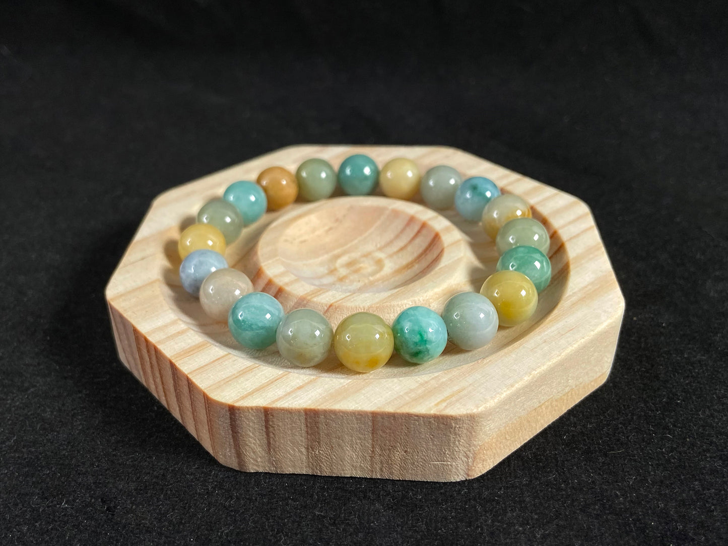 A strand of uniform jade beads in seafoam green, brown, yellow, light yellow green, forest green and lavender white.
