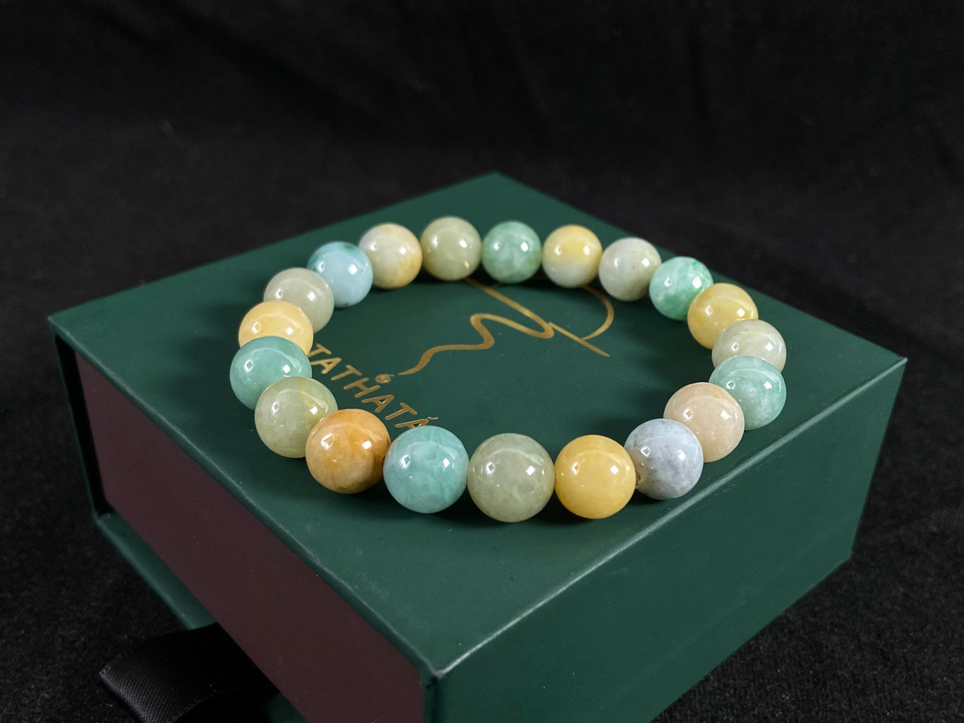 A strand of uniform jade beads in seafoam green, brown, yellow, light yellow green, forest green and lavender white.