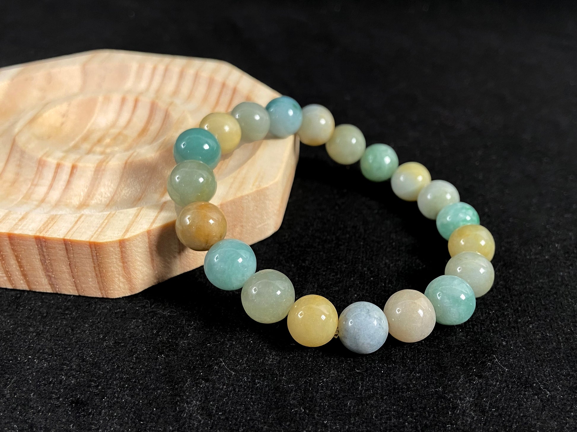 A strand of uniform jade beads in seafoam green, brown, yellow, light yellow green, forest green and lavender white.