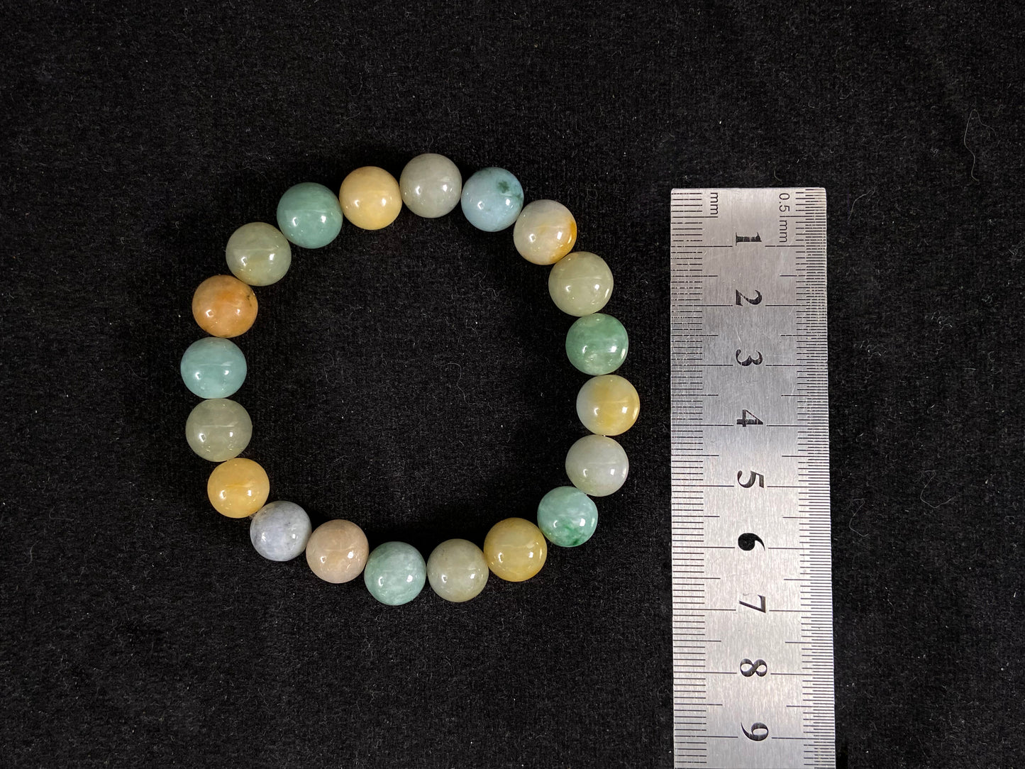 A strand of uniform jade beads in seafoam green, brown, yellow, light yellow green, forest green and lavender white.