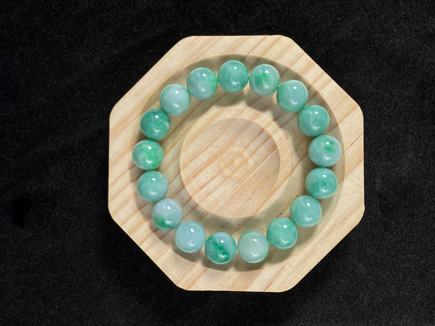 A jade bead strand featuring unique white green tones in varying shades.