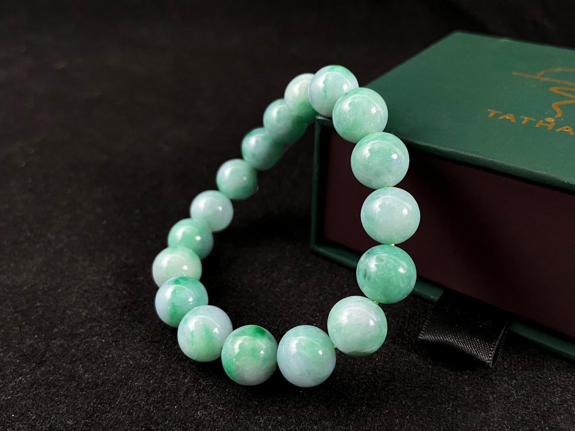 A jade bead strand featuring unique white green tones in varying shades.