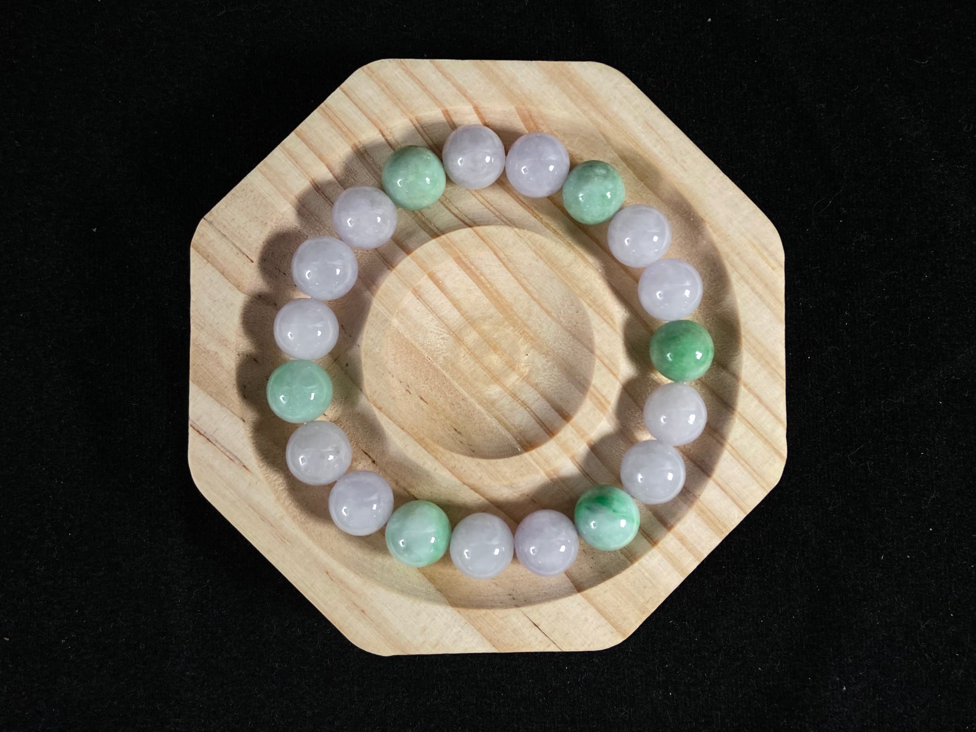 A strand of uniform pale lavender-white jade beads featuring six strategically placed icy green white accent beads.