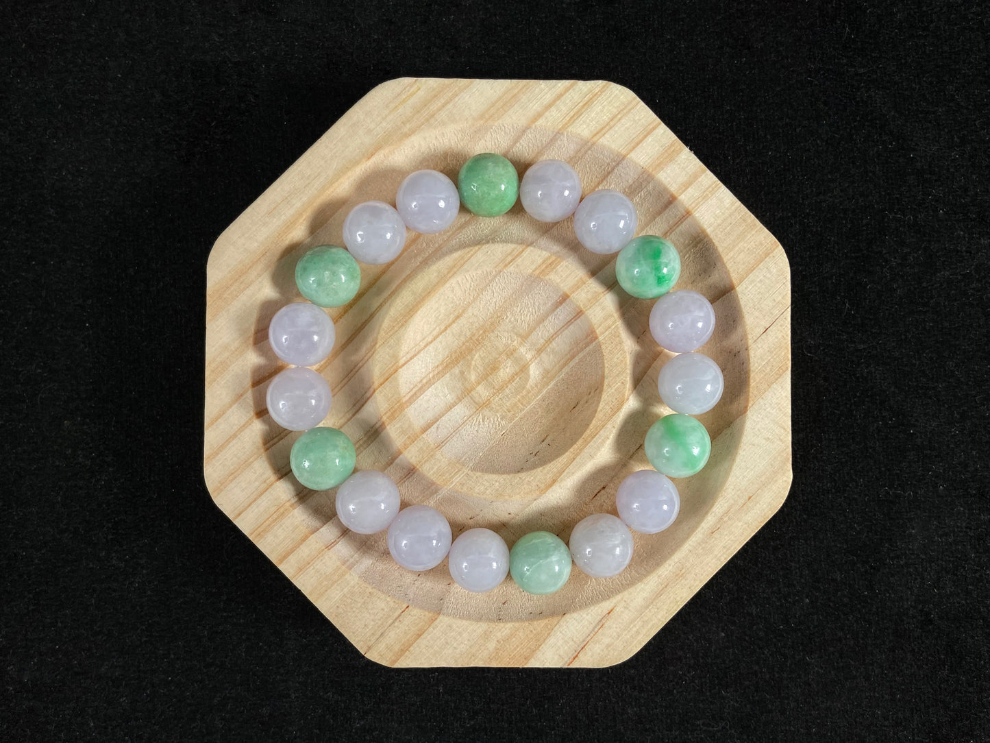 A strand of uniform pale lavender-white jade beads featuring six strategically placed icy green white accent beads.