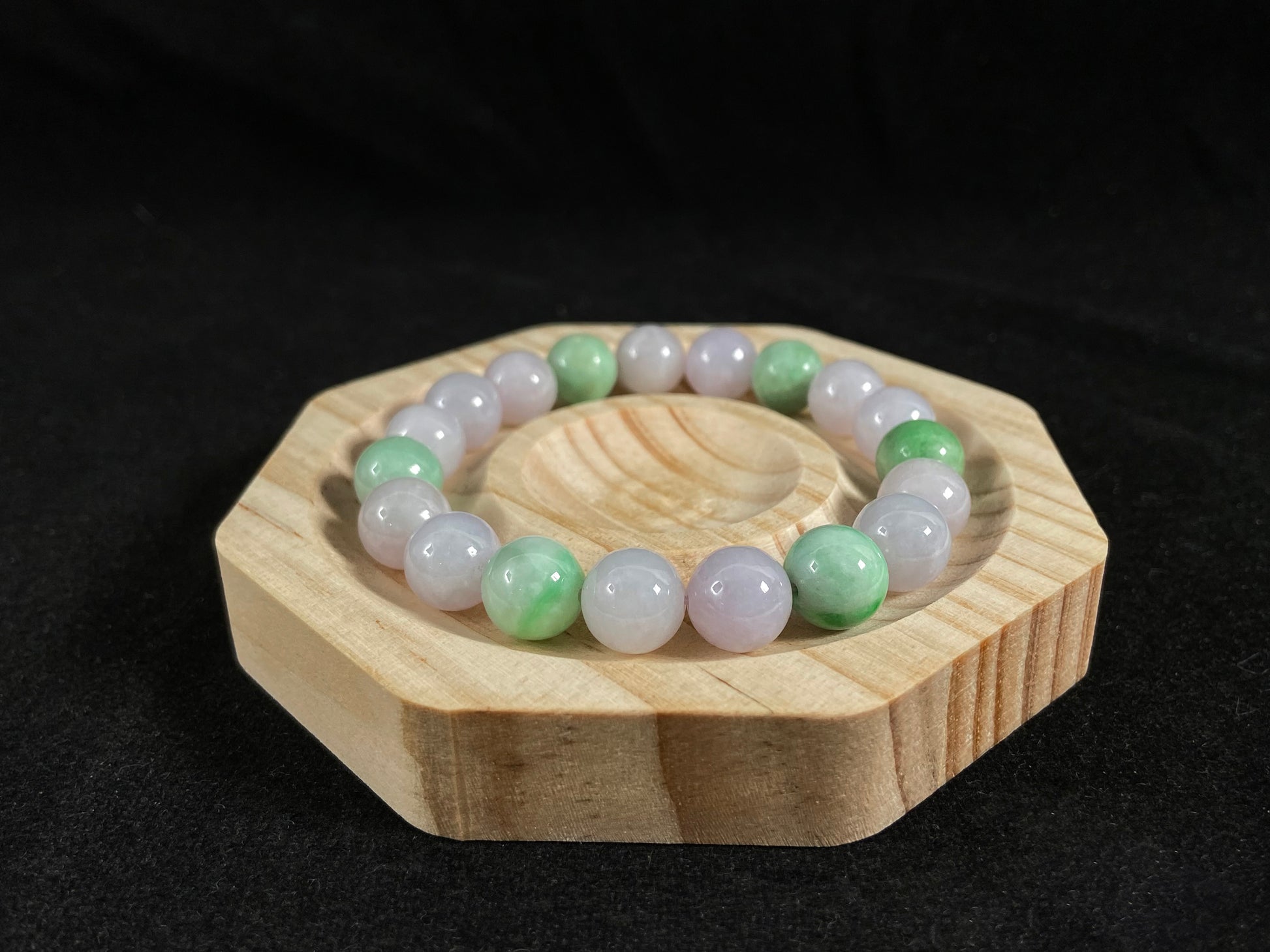 A strand of uniform pale lavender-white jade beads featuring six strategically placed icy green white accent beads.