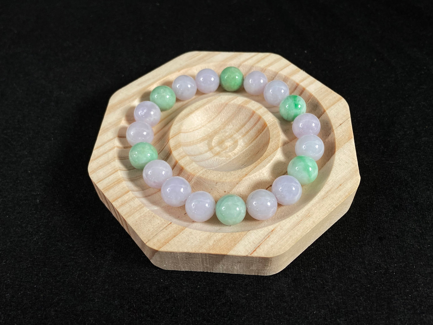 A strand of uniform pale lavender-white jade beads featuring six strategically placed icy green white accent beads.