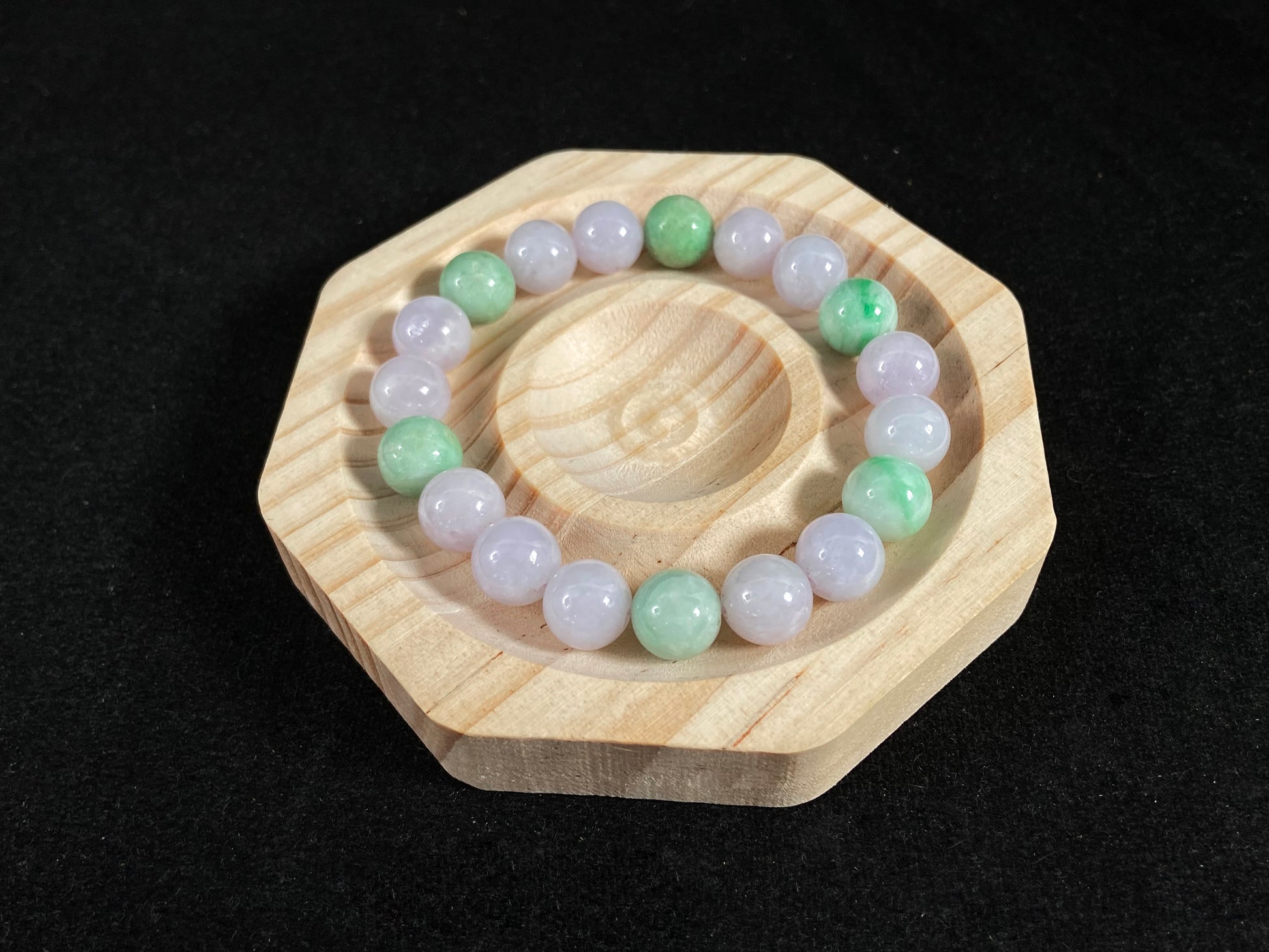 A strand of uniform pale lavender-white jade beads featuring six strategically placed icy green white accent beads.