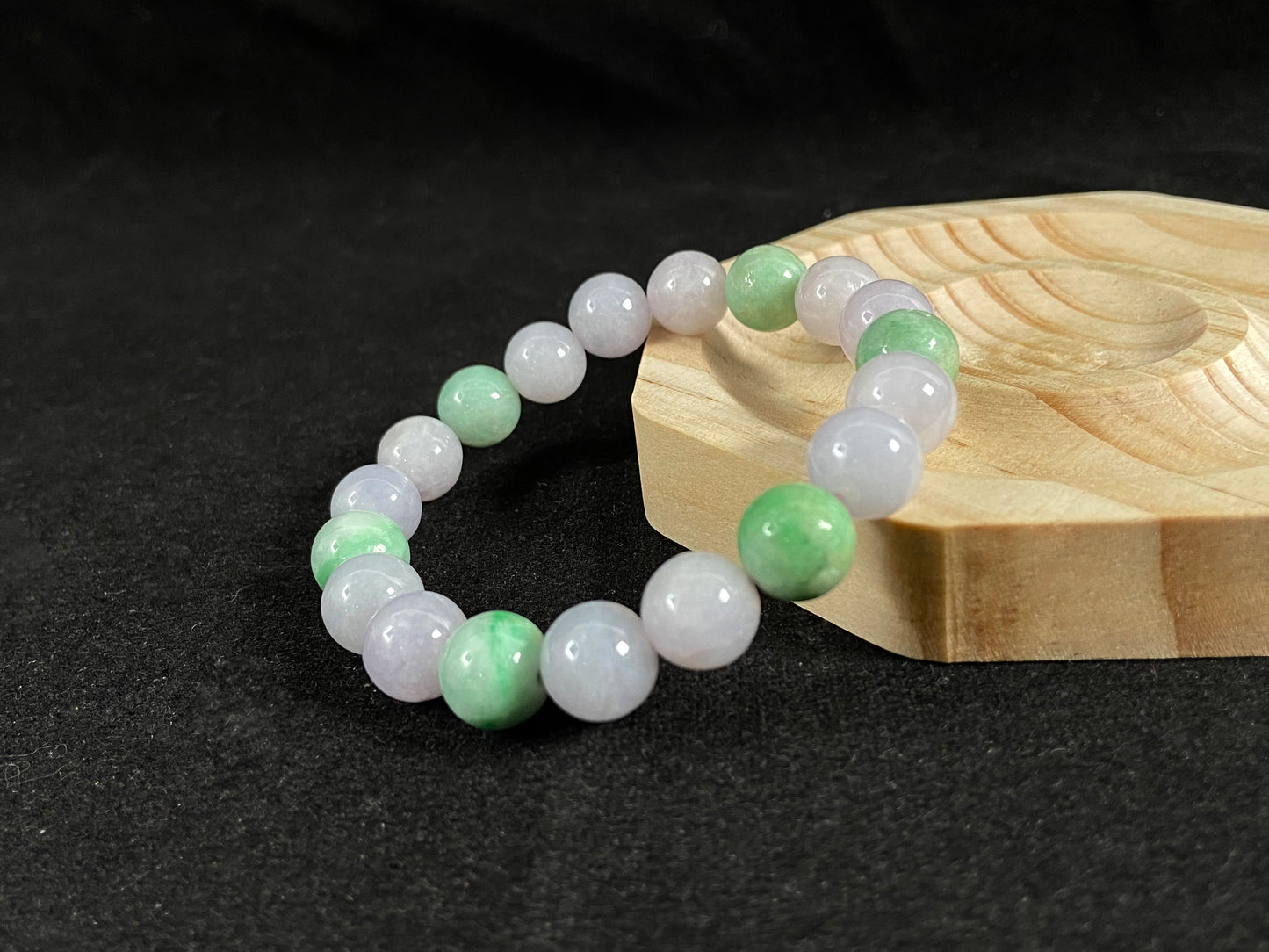 A strand of uniform pale lavender-white jade beads featuring six strategically placed icy green white accent beads.