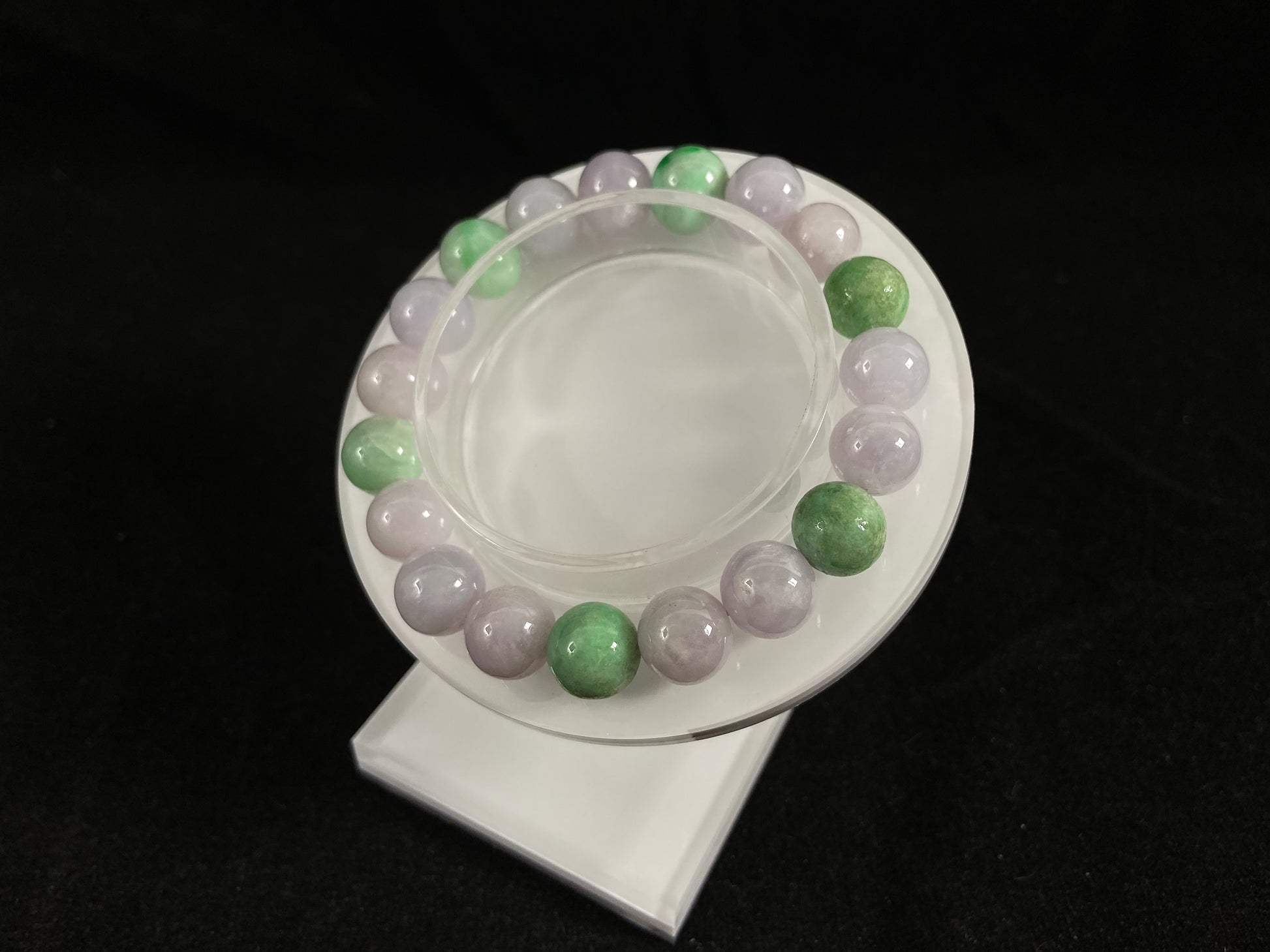A strand of uniform pale lavender-white jade beads featuring six strategically placed icy green white accent beads.