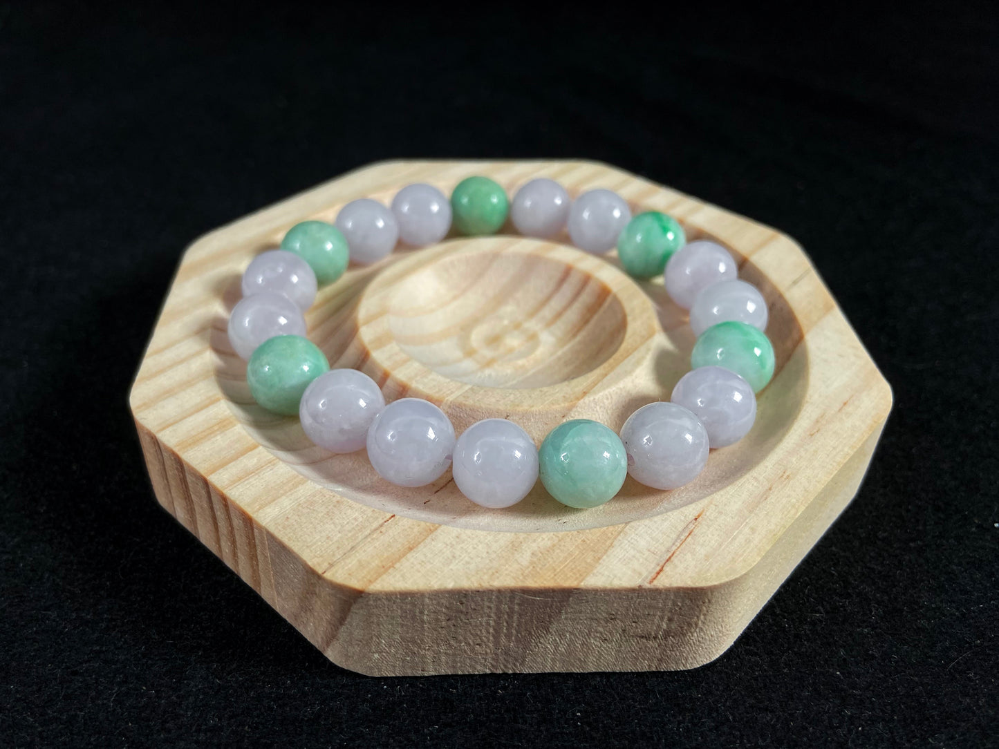 A strand of uniform pale lavender-white jade beads featuring six strategically placed icy green white accent beads.