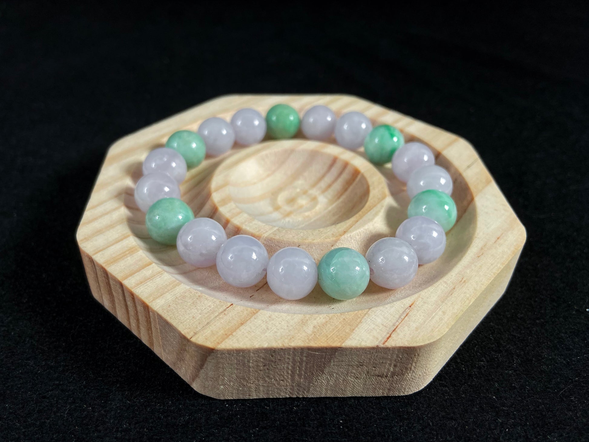 A strand of uniform pale lavender-white jade beads featuring six strategically placed icy green white accent beads.