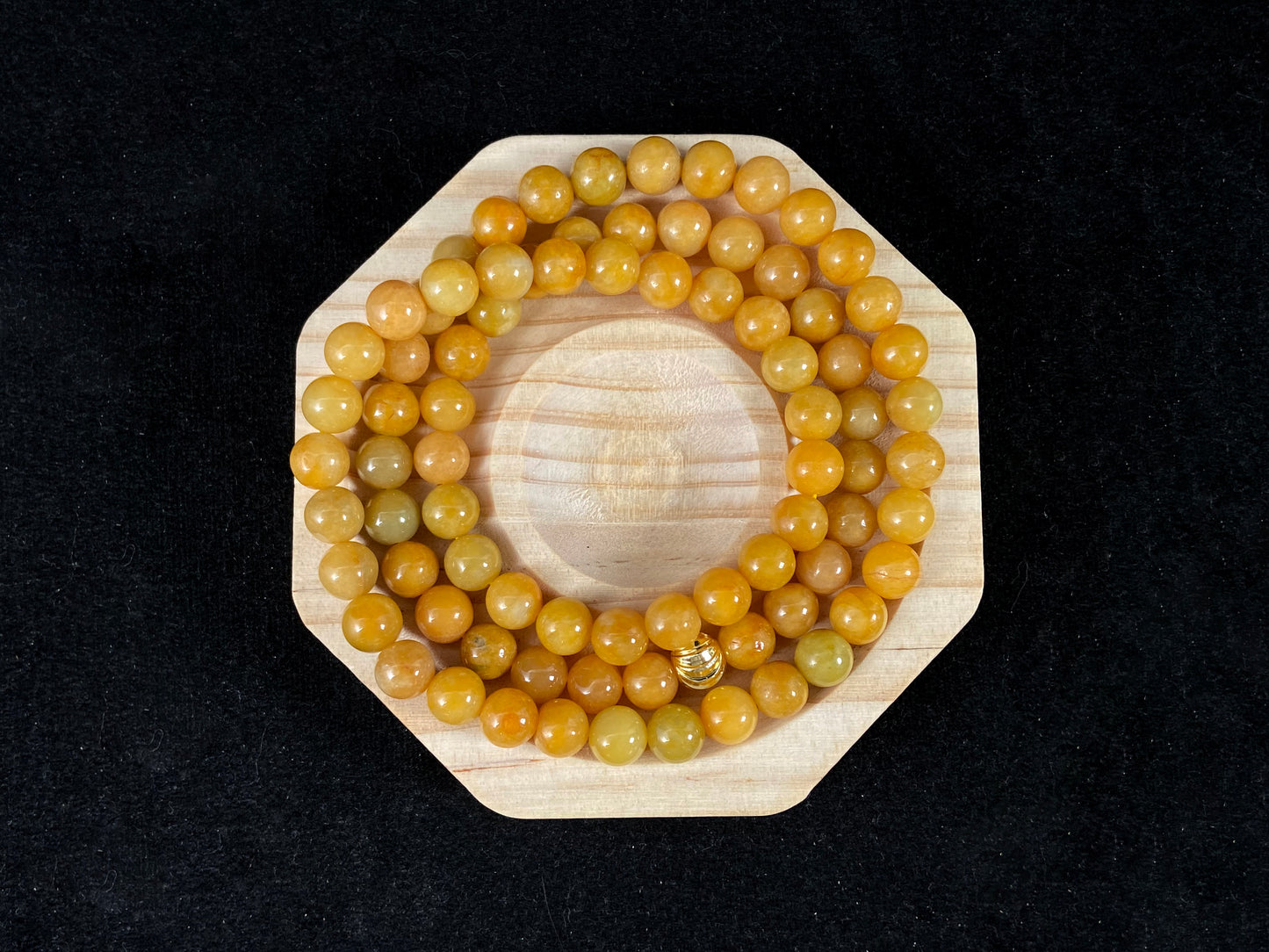 A strand of yellow jade beads featuring an alloy accented piece.