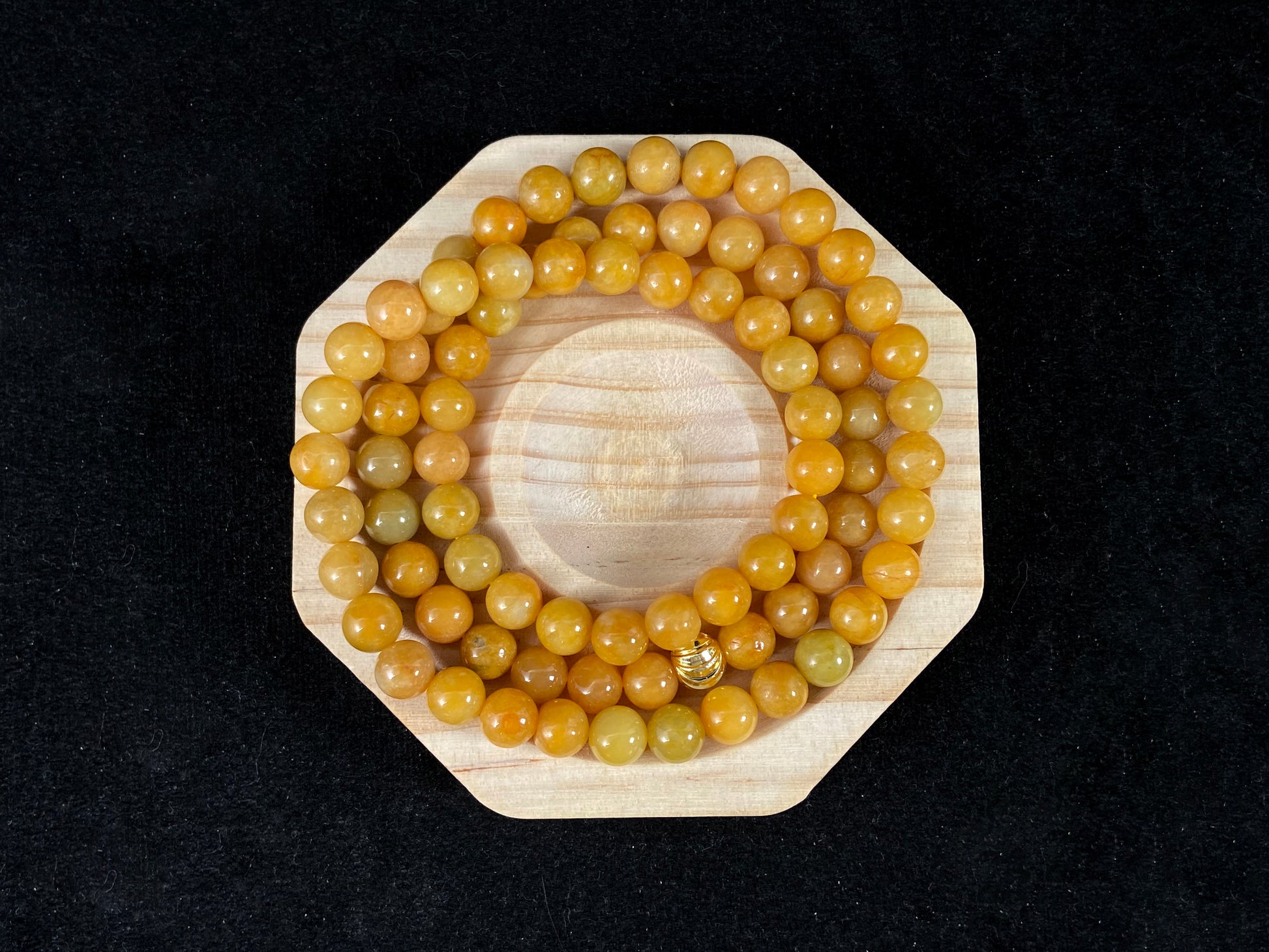 A strand of yellow jade beads featuring an alloy accented piece.