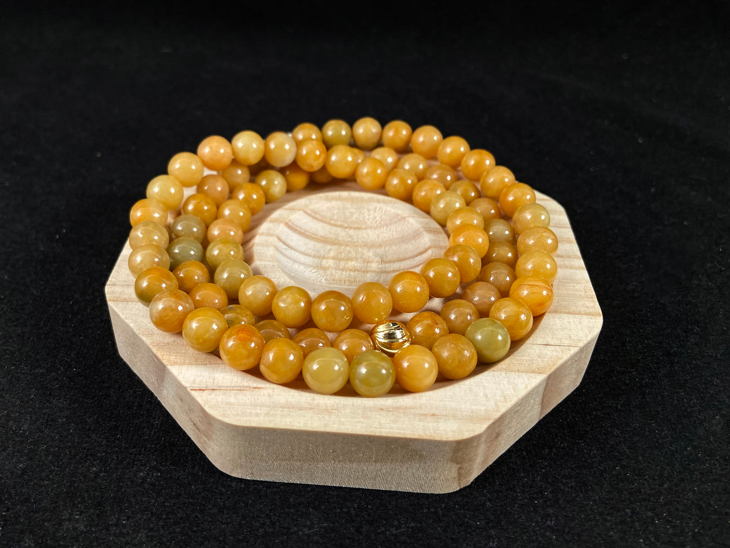 A strand of yellow jade beads featuring an alloy accented piece.
