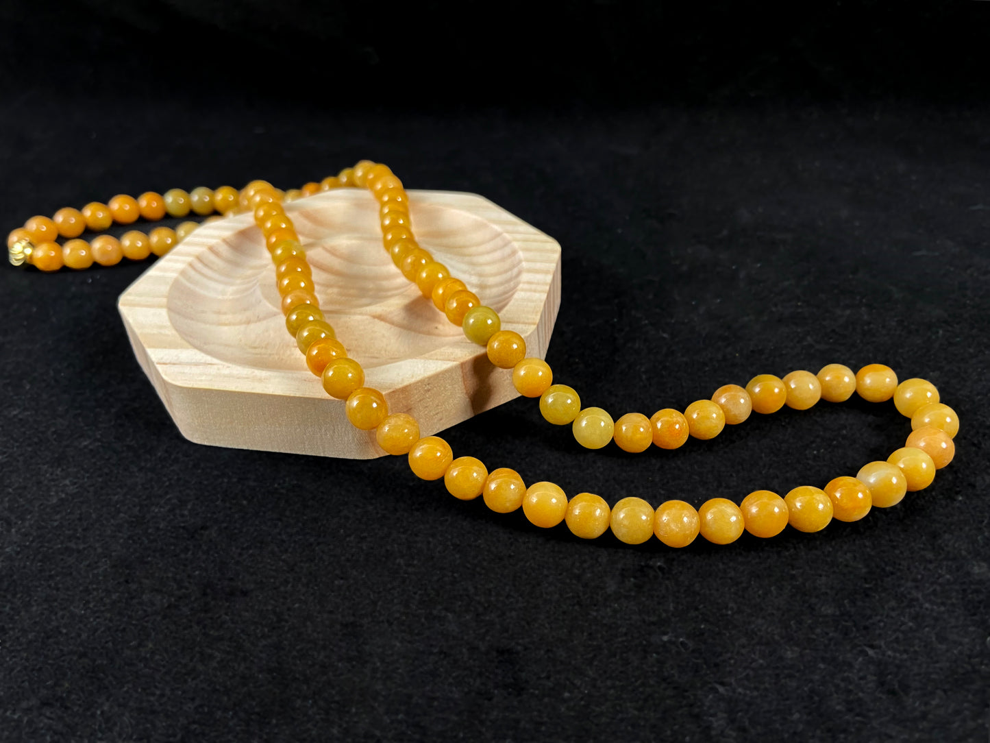 A strand of yellow jade beads featuring an alloy accented piece.
