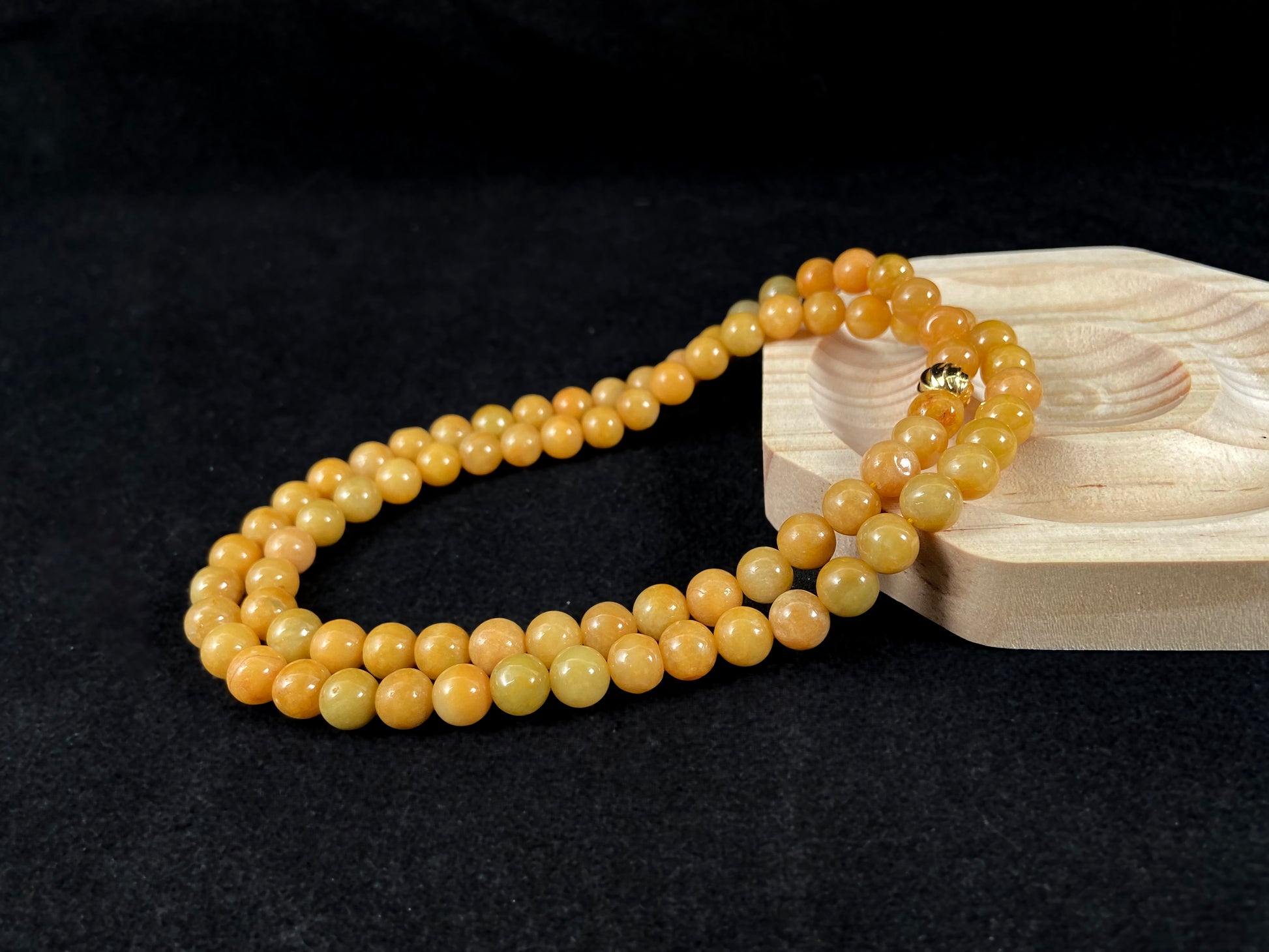 A strand of yellow jade beads featuring an alloy accented piece.