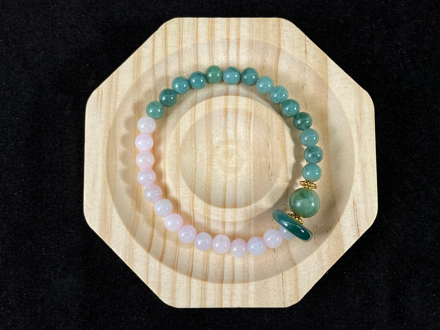 A dual color jade strand: translucent white and green small beads, green round clasp, large center bead with alloy accents.