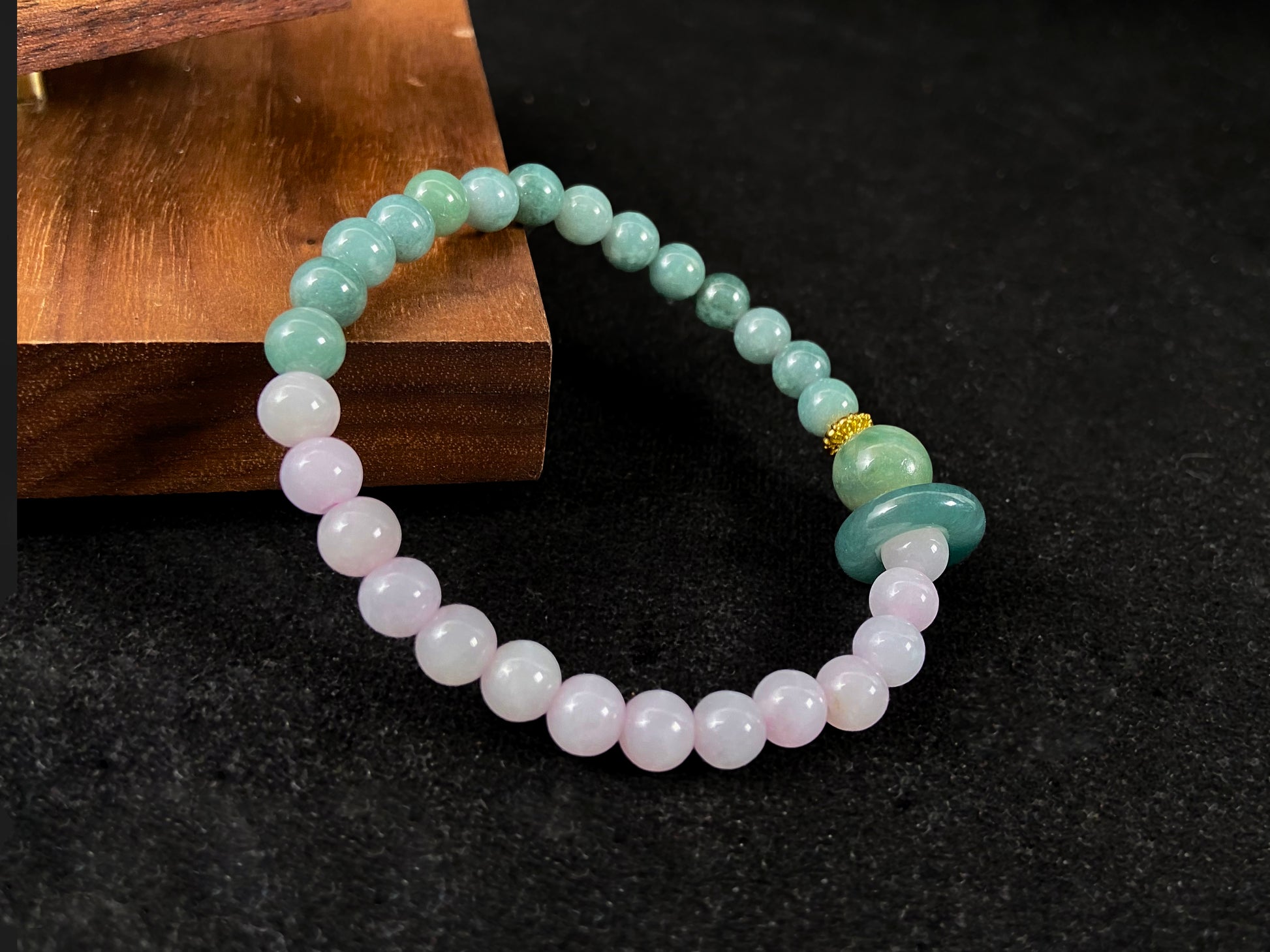 A dual color jade strand: translucent white and green small beads, green round clasp, large center bead with alloy accents.