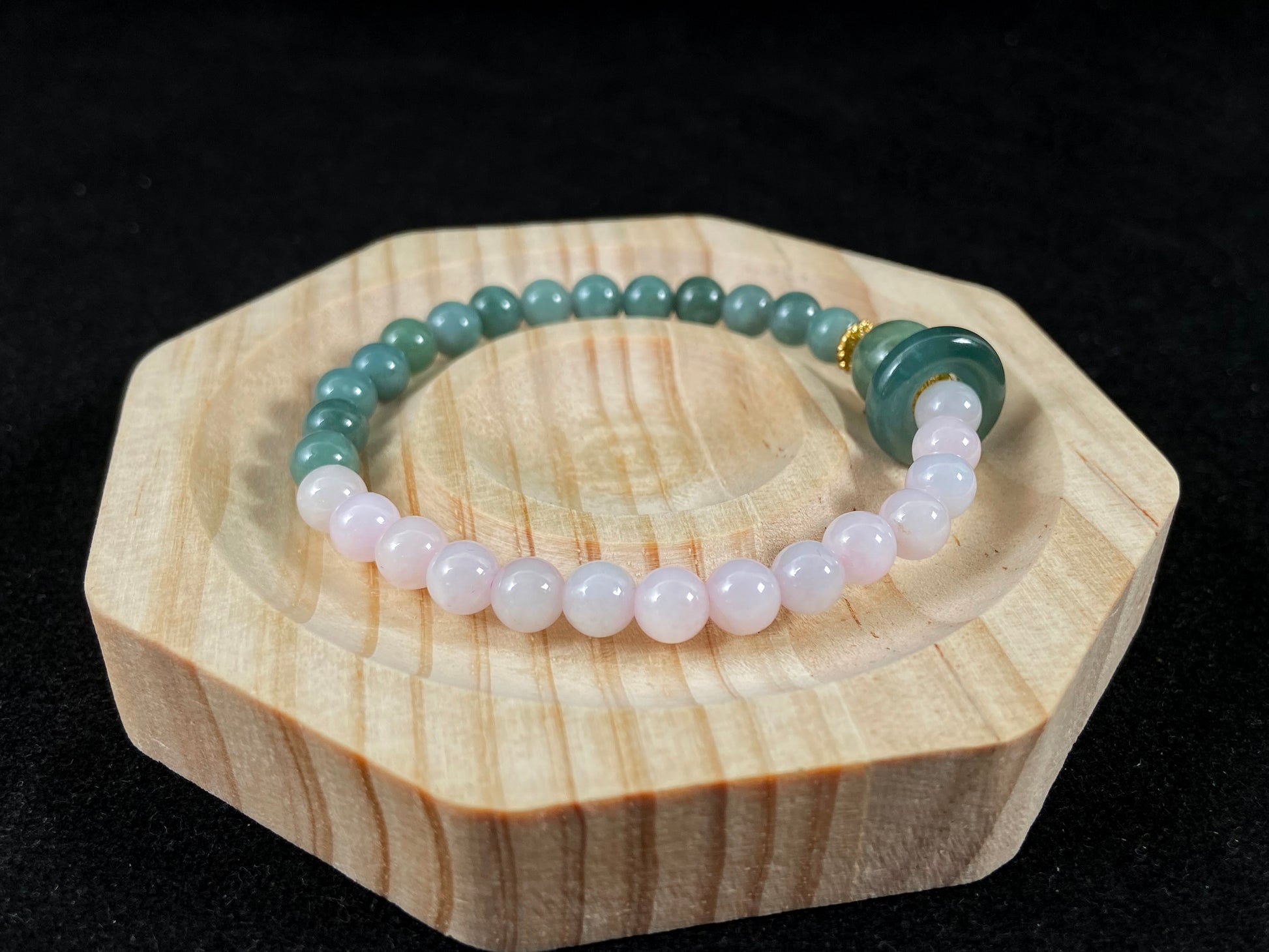 A dual color jade strand: translucent white and green small beads, green round clasp, large center bead with alloy accents.