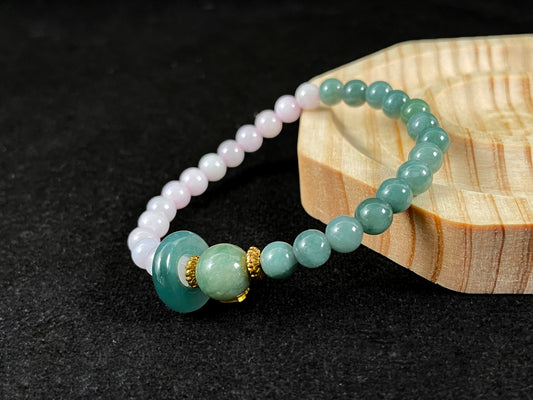 A dual color jade strand: translucent white and green small beads, green round clasp, large center bead with alloy accents.