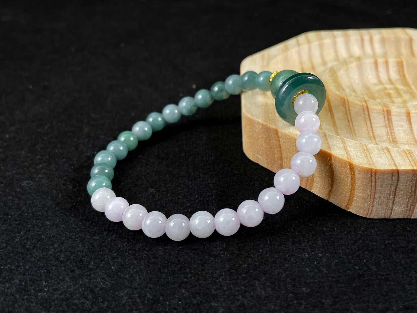 A dual color jade strand: translucent white and green small beads, green round clasp, large center bead with alloy accents.