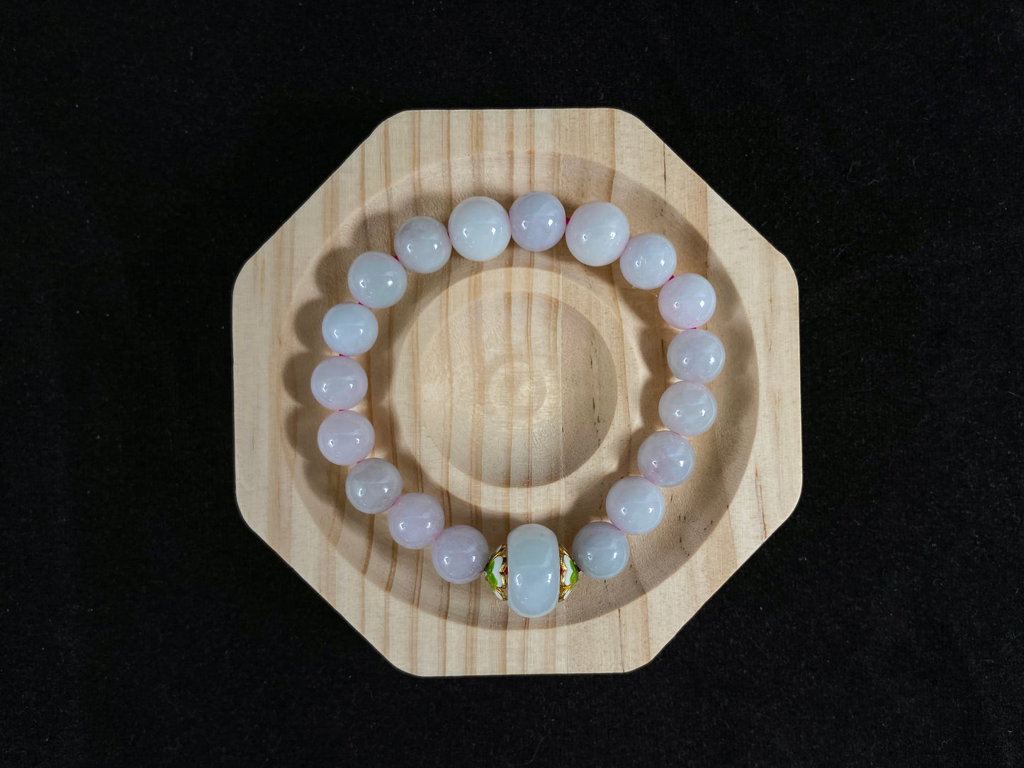 A milky white jade bead strand featuring a central focal bead accented with white green petal shaped alloy sidepieces.