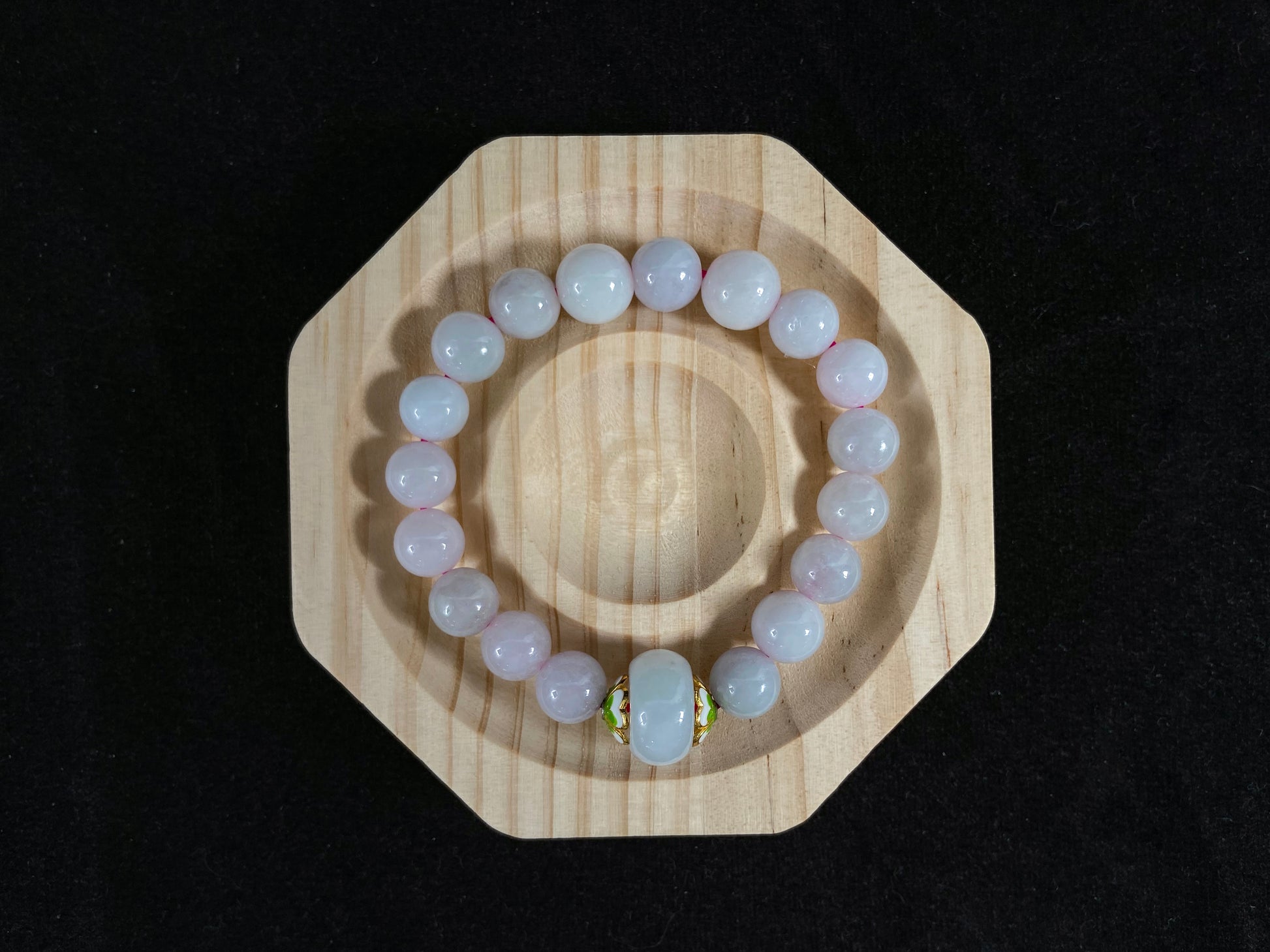 A milky white jade bead strand featuring a central focal bead accented with white green petal shaped alloy sidepieces.