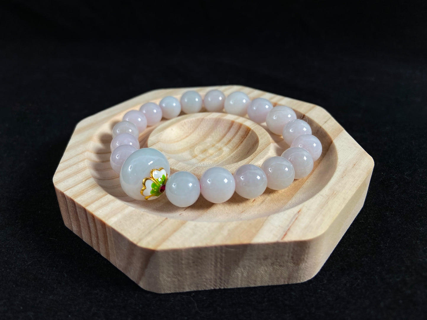 A milky white jade bead strand featuring a central focal bead accented with white green petal shaped alloy sidepieces.