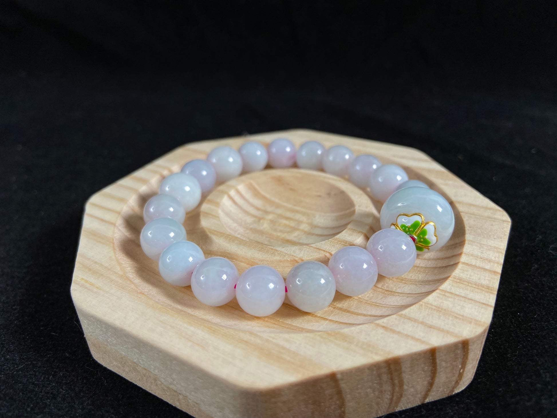 A milky white jade bead strand featuring a central focal bead accented with white green petal shaped alloy sidepieces.