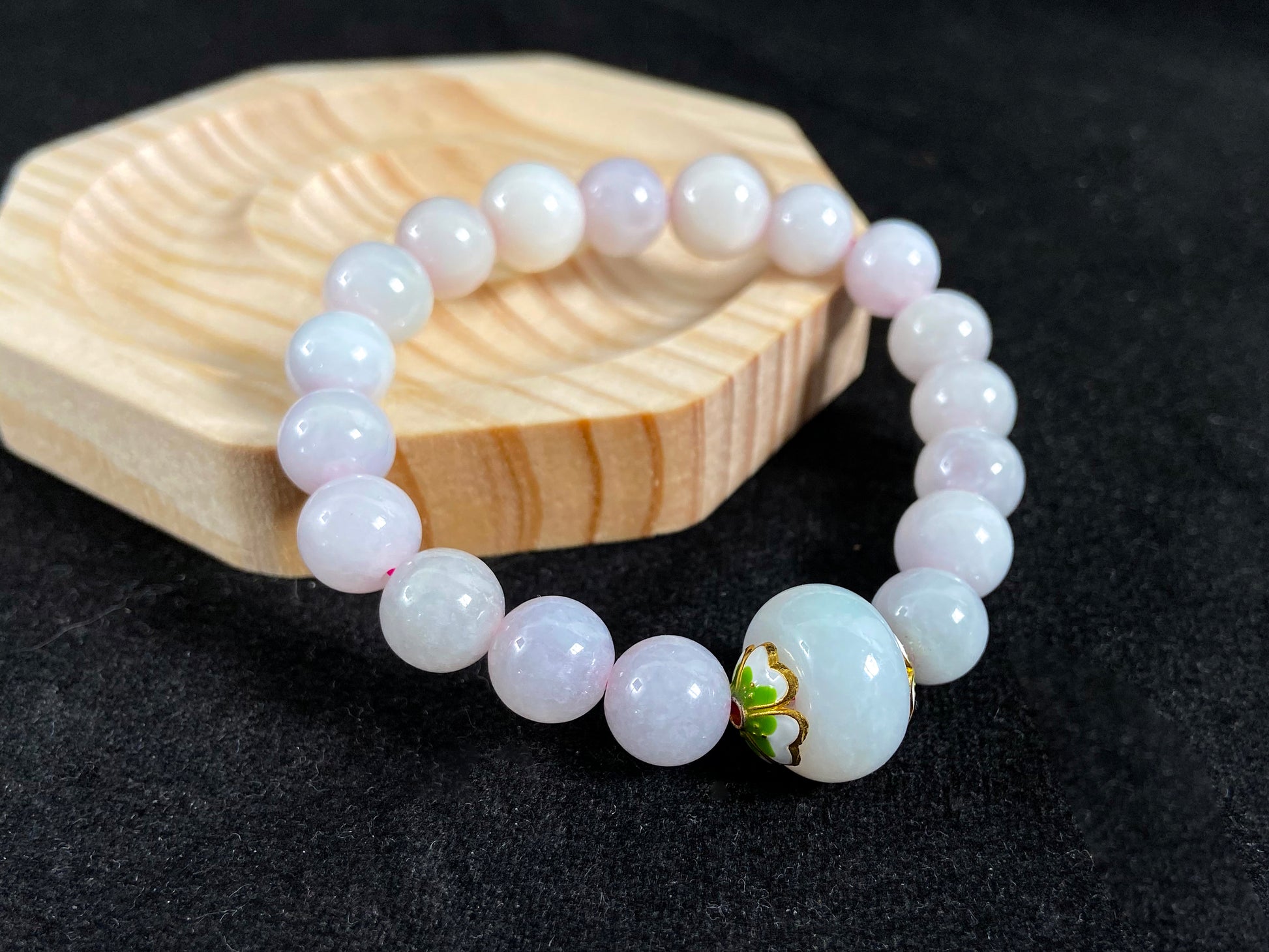A milky white jade bead strand featuring a central focal bead accented with white green petal shaped alloy sidepieces.