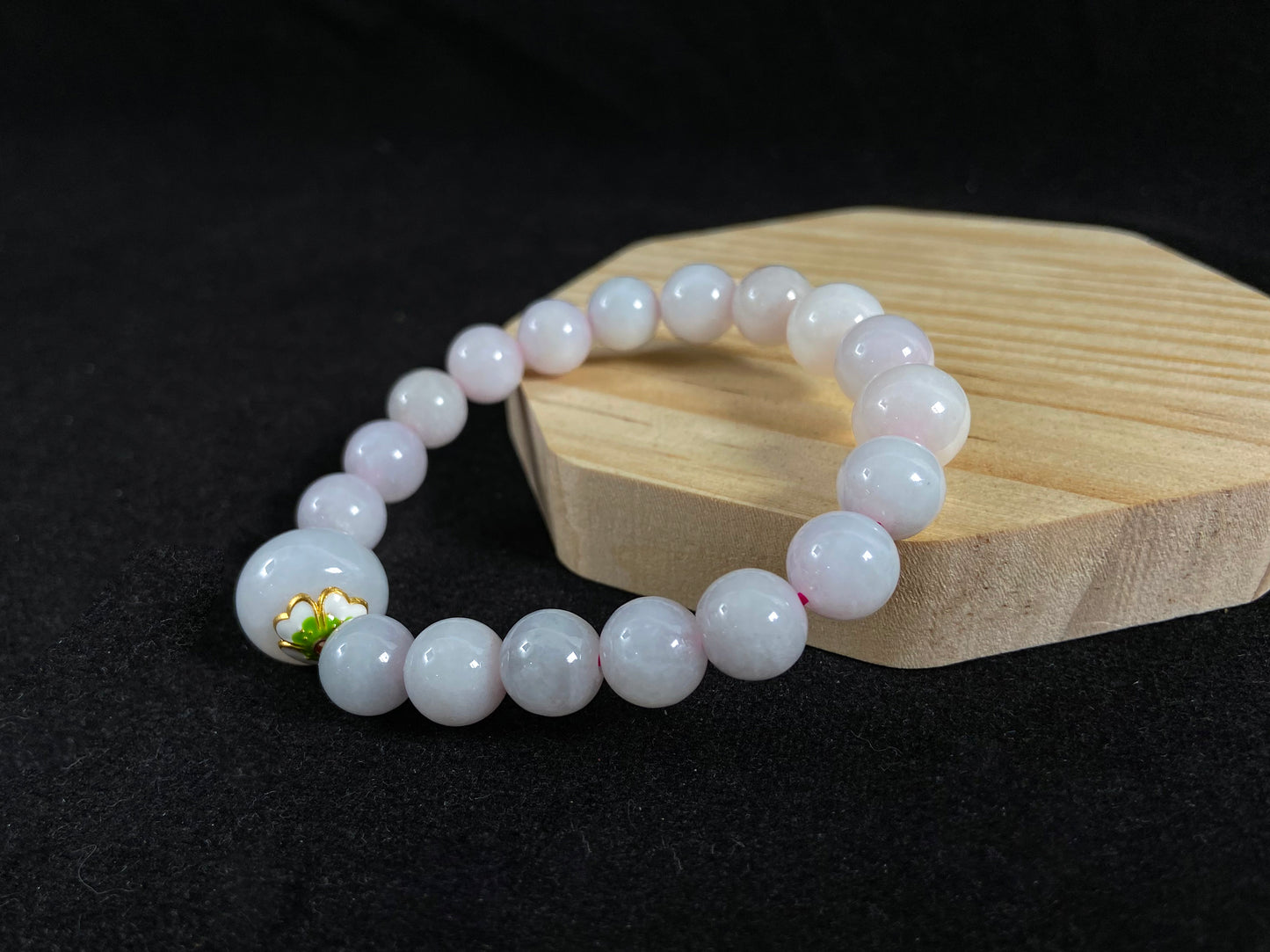 A milky white jade bead strand featuring a central focal bead accented with white green petal shaped alloy sidepieces.