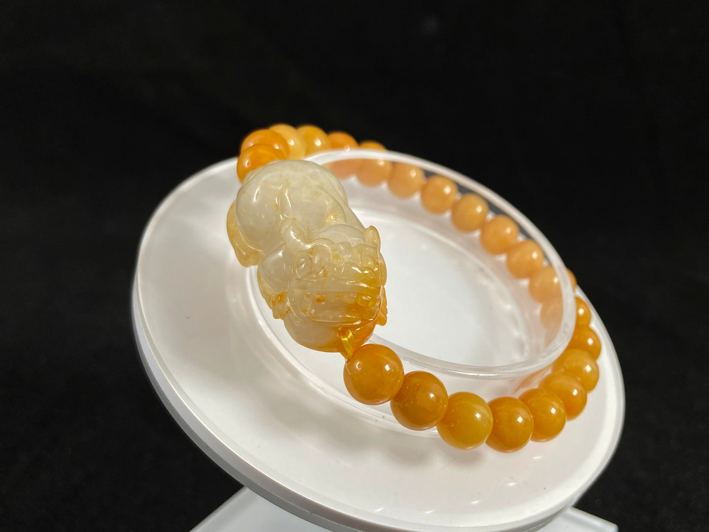 A jade bead strand featuring a white based gold flecked pixiu charm and yellow beads.