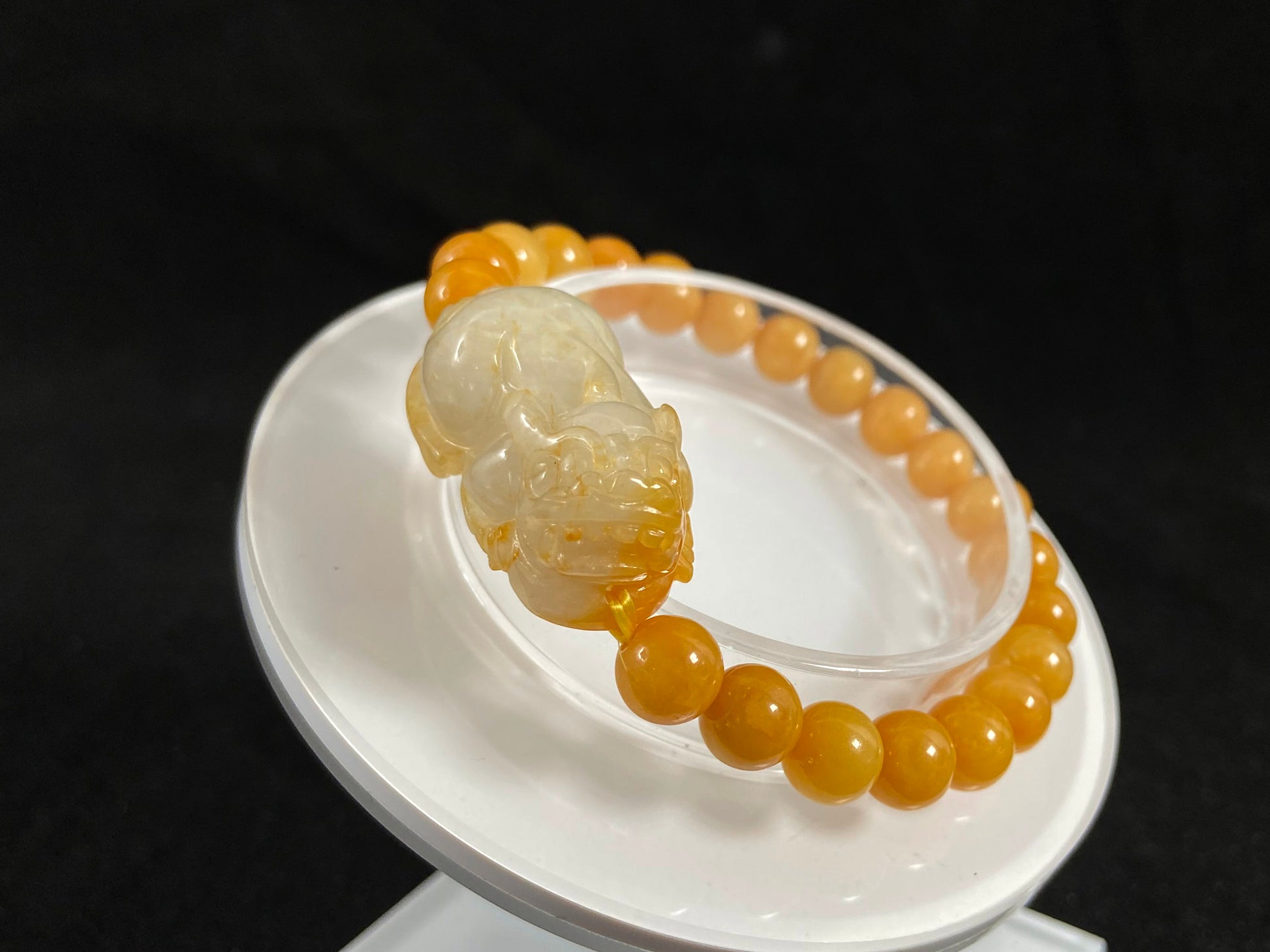 A jade bead strand featuring a white based gold flecked pixiu charm and yellow beads.