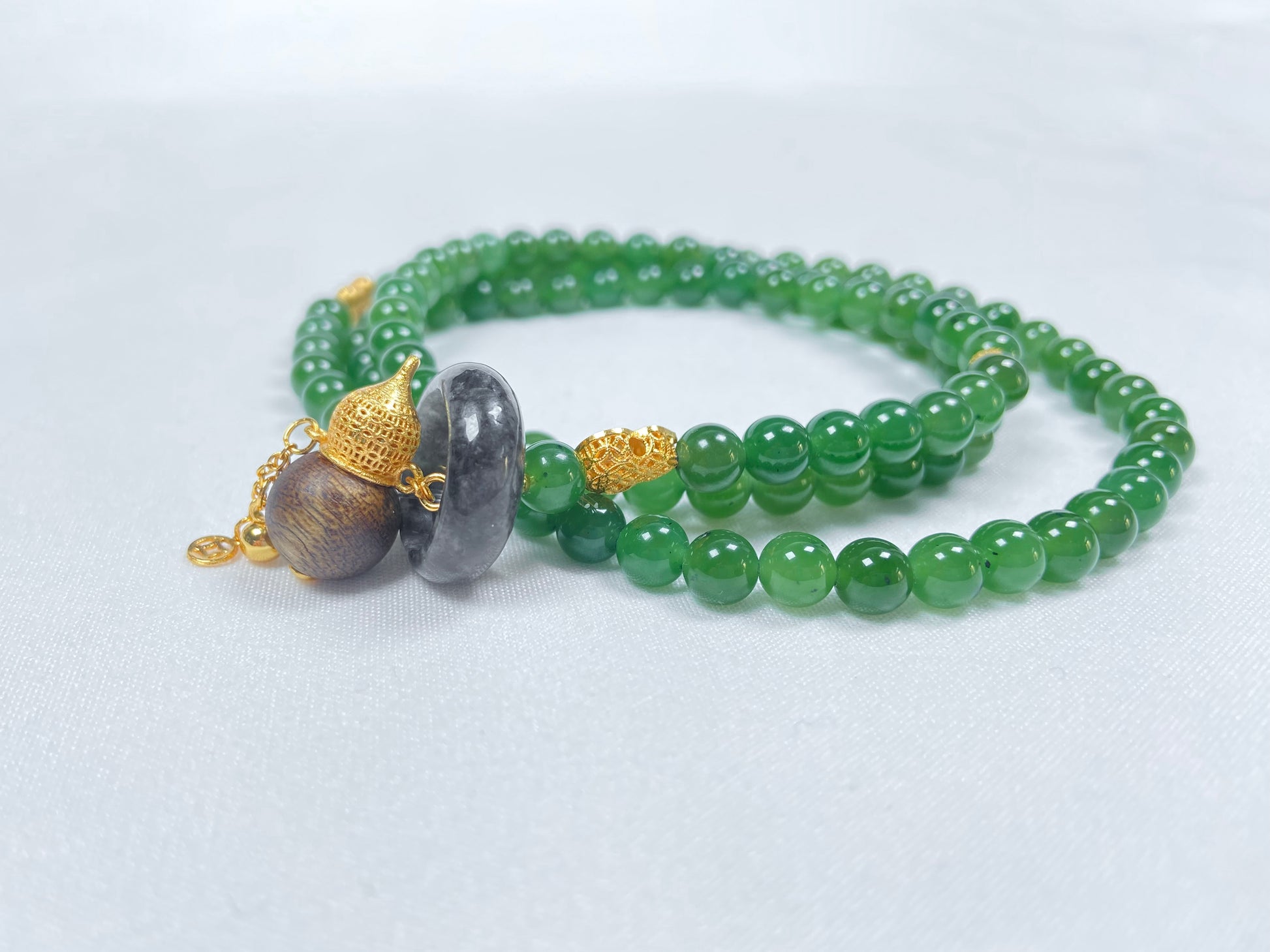 A green Hetian Jade, agarwood, and Wuji jadeite silver necklace.