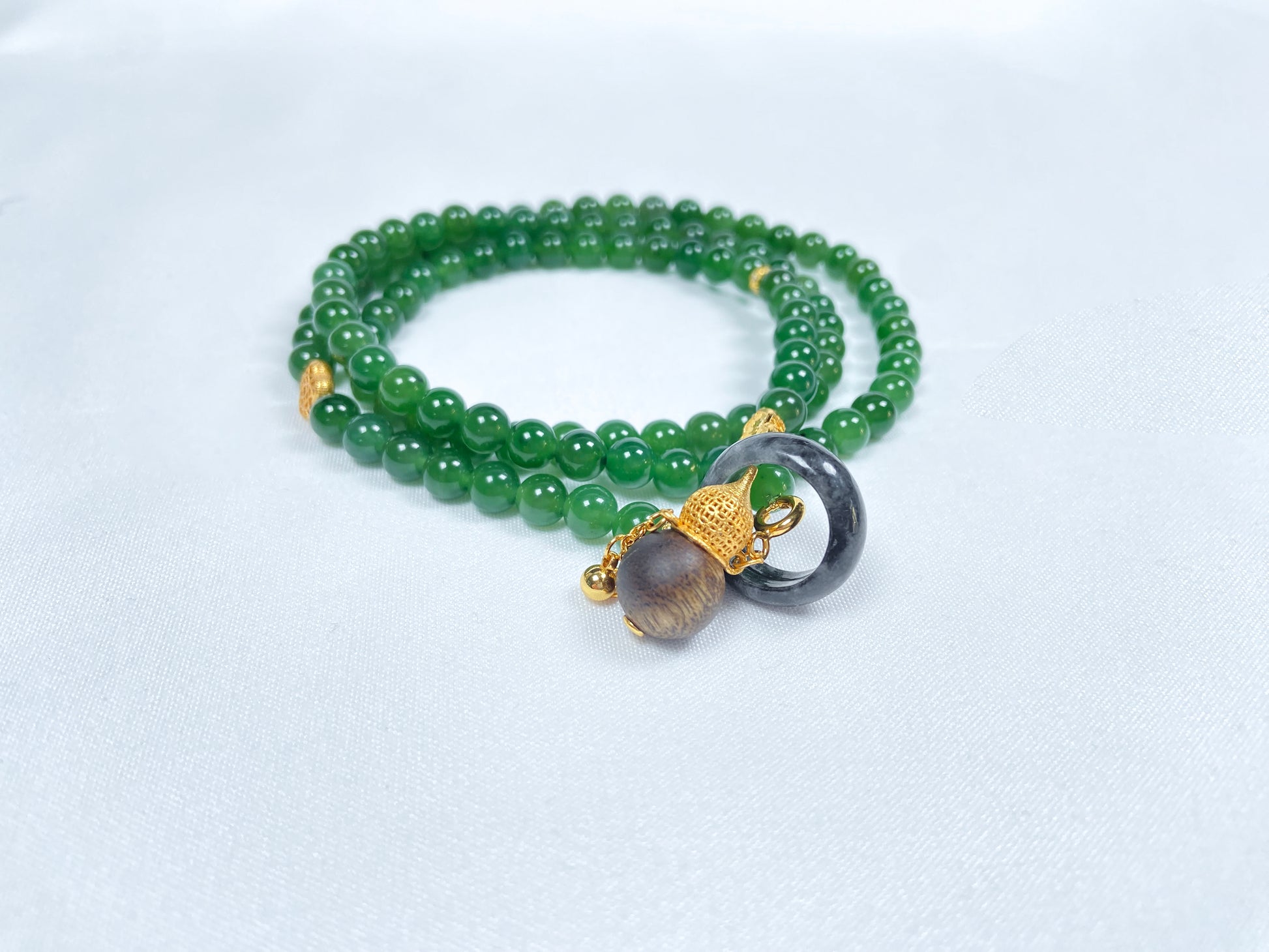A green Hetian Jade, agarwood, and Wuji jadeite silver necklace.