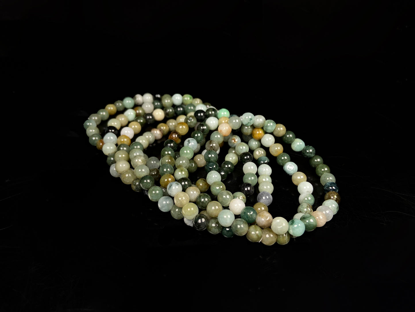 A group of jadeite beaded bracelets is made of mixed green, yellow, gray and black beads.