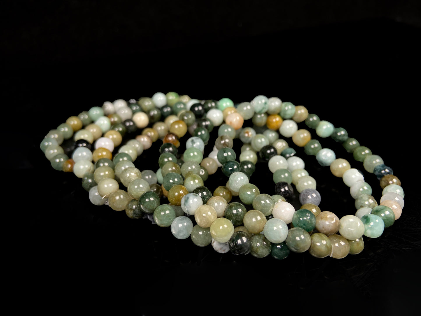 A group of jadeite beaded bracelets is made of mixed green, yellow, gray and black beads.