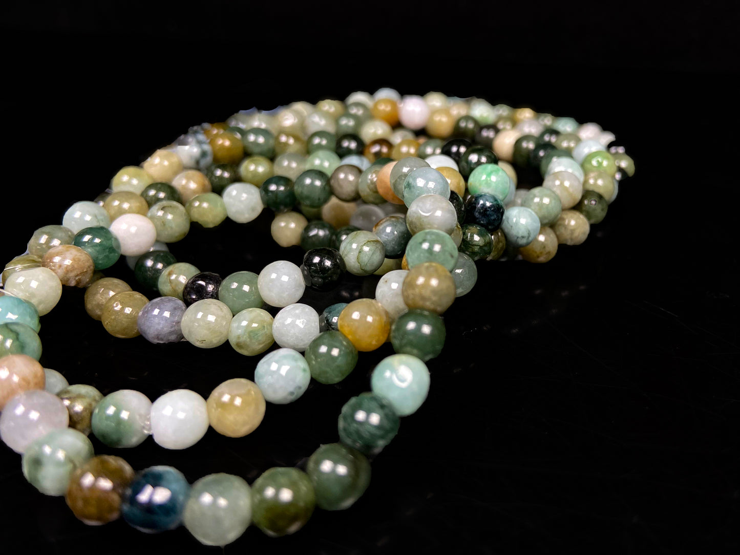A group of jadeite beaded bracelets is made of mixed green, yellow, gray and black beads.