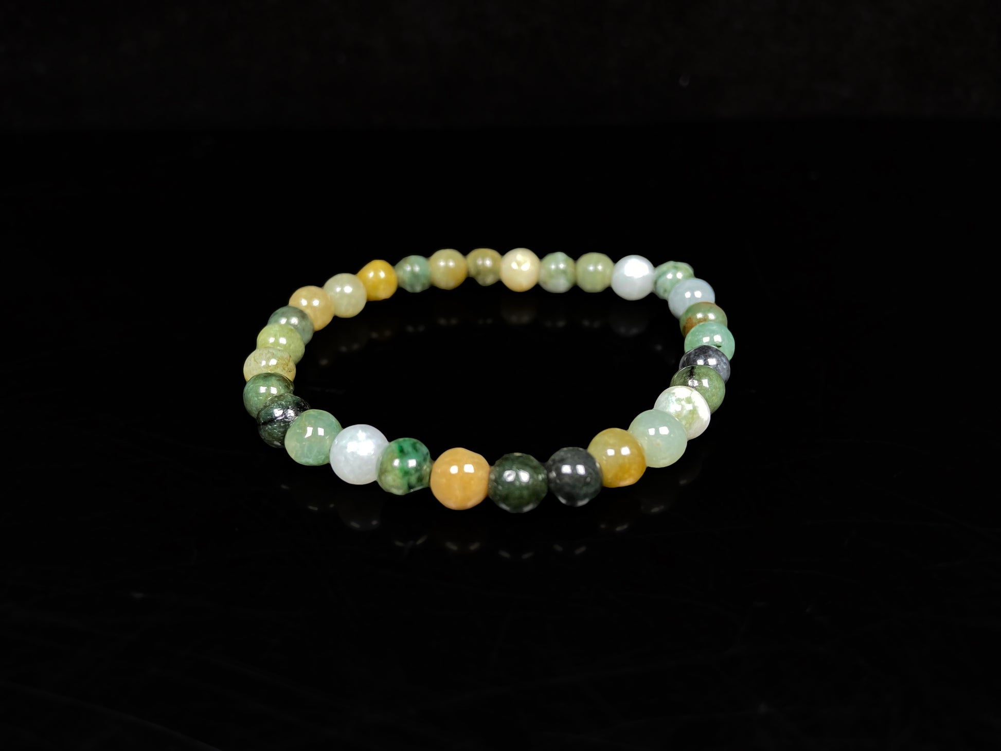 A jadeite beaded bracelets is made of mixed green, yellow, gray and black beads.