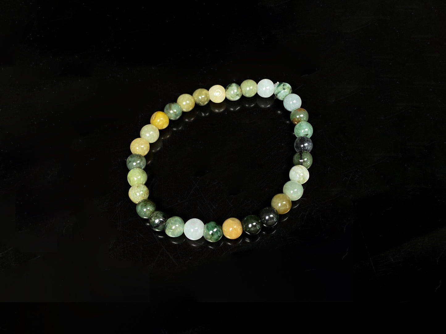 A  jadeite beaded bracelets is made of mixed green, yellow, gray and black beads.
