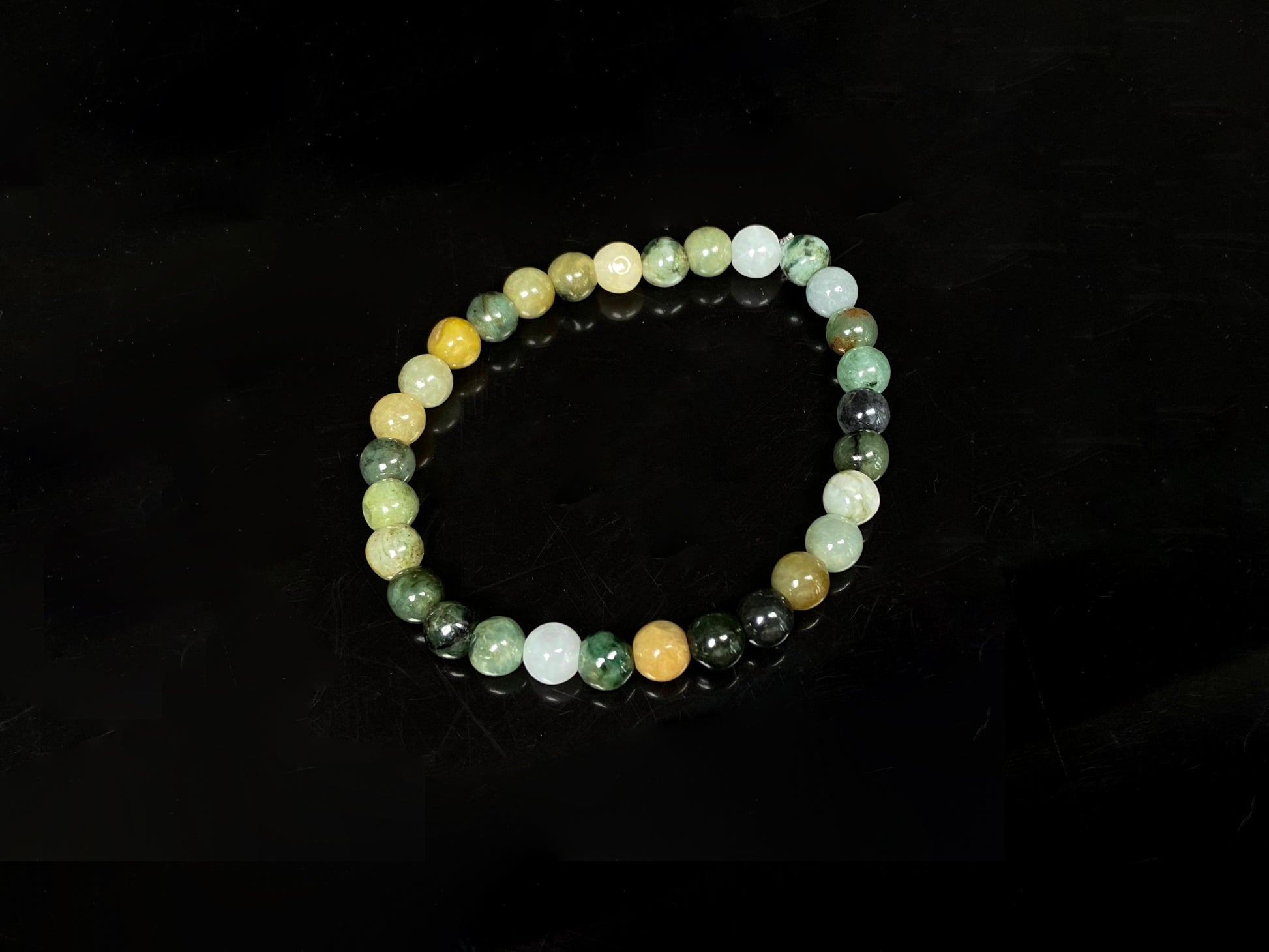 A  jadeite beaded bracelets is made of mixed green, yellow, gray and black beads.