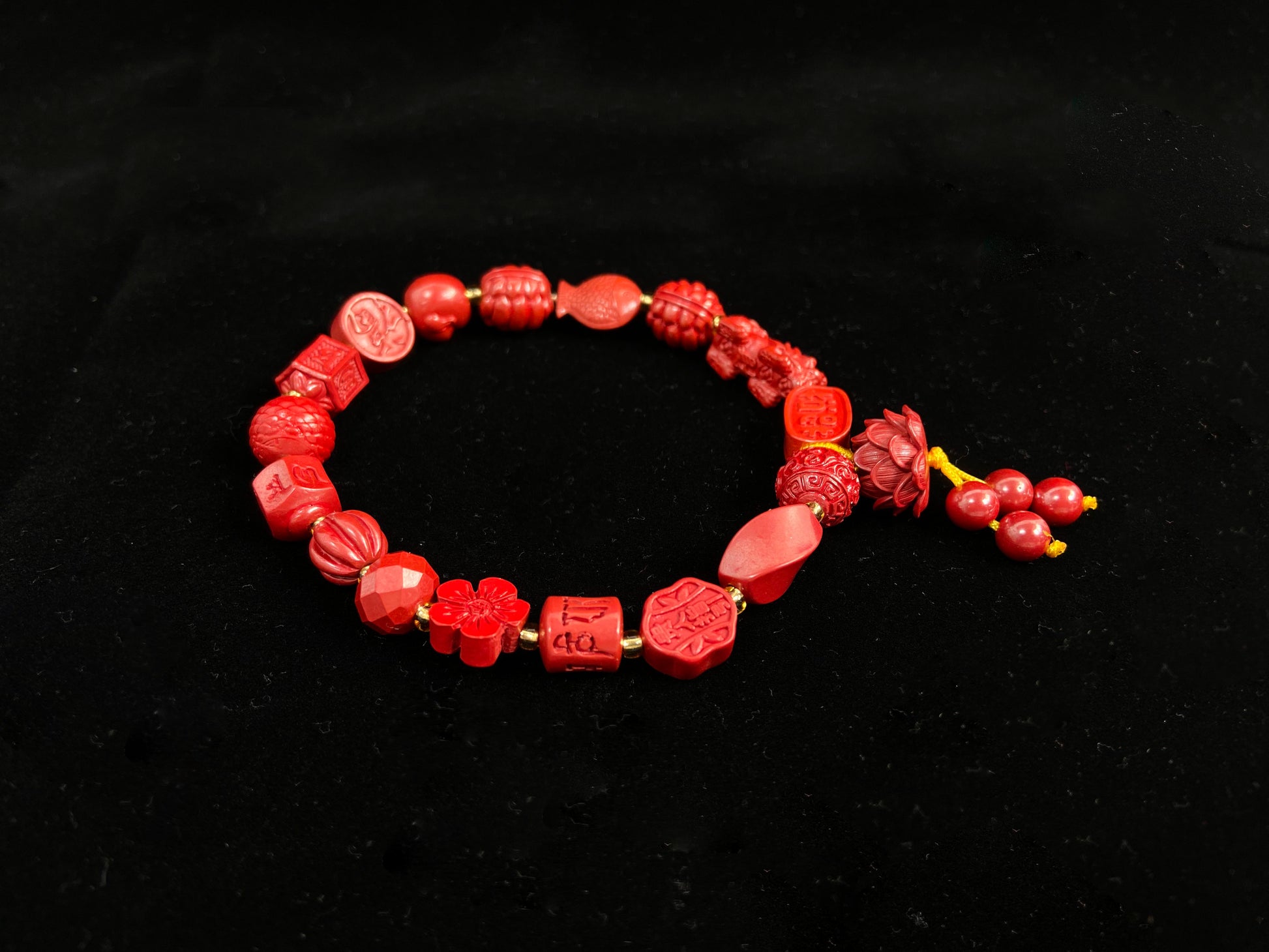This cinnabar bracelet showcases an array of symbolic beads in pumpkin, peach blossom, fortune, and fish shapes, complete with a lotus charm and four rotating beads.