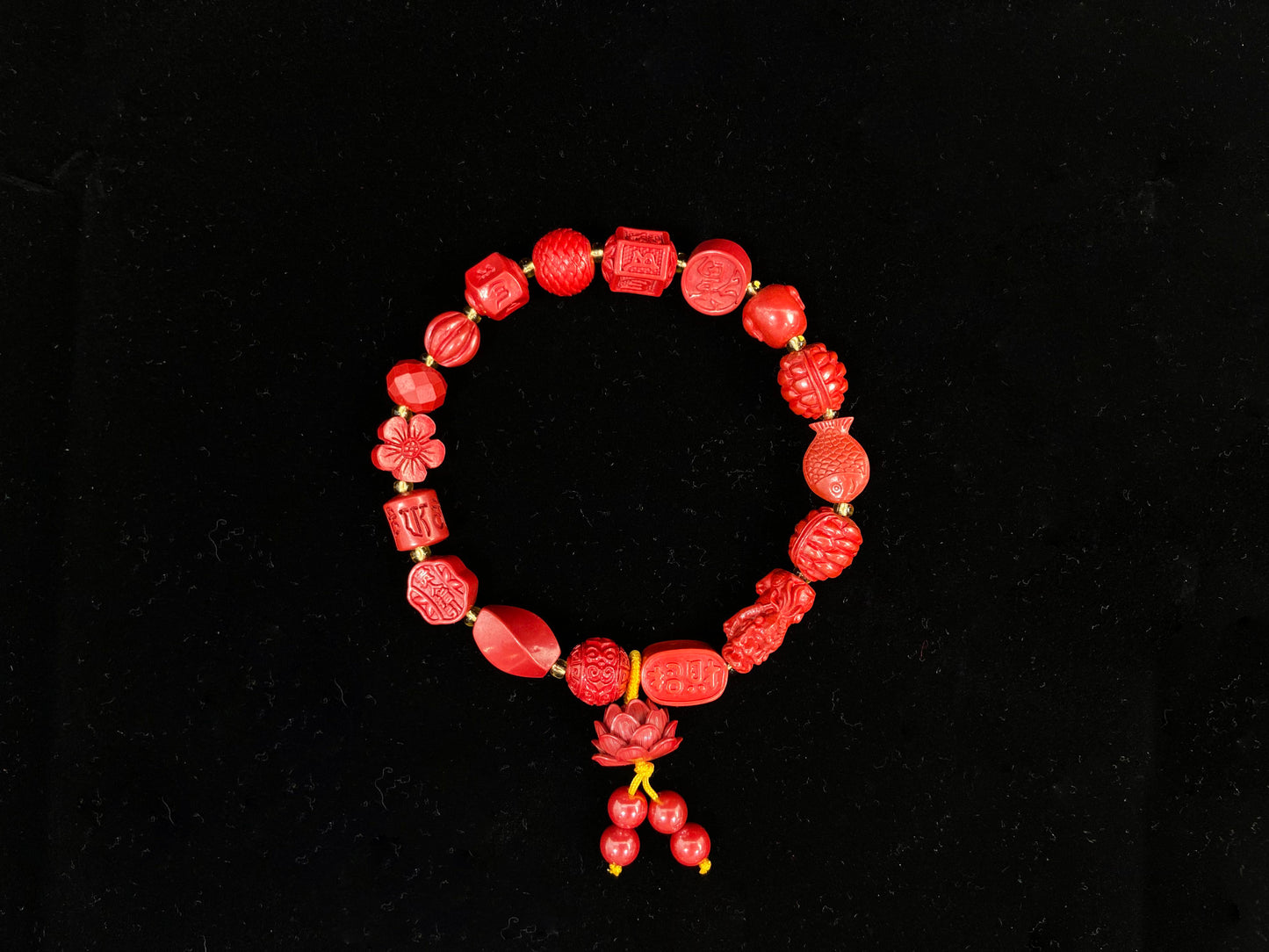 This cinnabar bracelet showcases an array of symbolic beads in pumpkin, peach blossom, fortune, and fish shapes, complete with a lotus charm and four rotating beads.