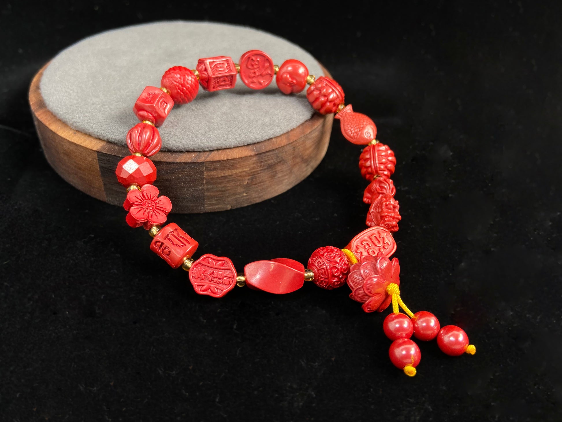 This cinnabar bracelet showcases an array of symbolic beads in pumpkin, peach blossom, fortune, and fish shapes, complete with a lotus charm and four rotating beads.