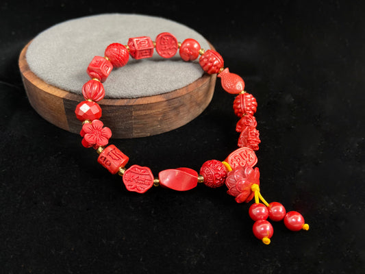 This cinnabar bracelet showcases an array of symbolic beads in pumpkin, peach blossom, fortune, and fish shapes, complete with a lotus charm and four rotating beads.